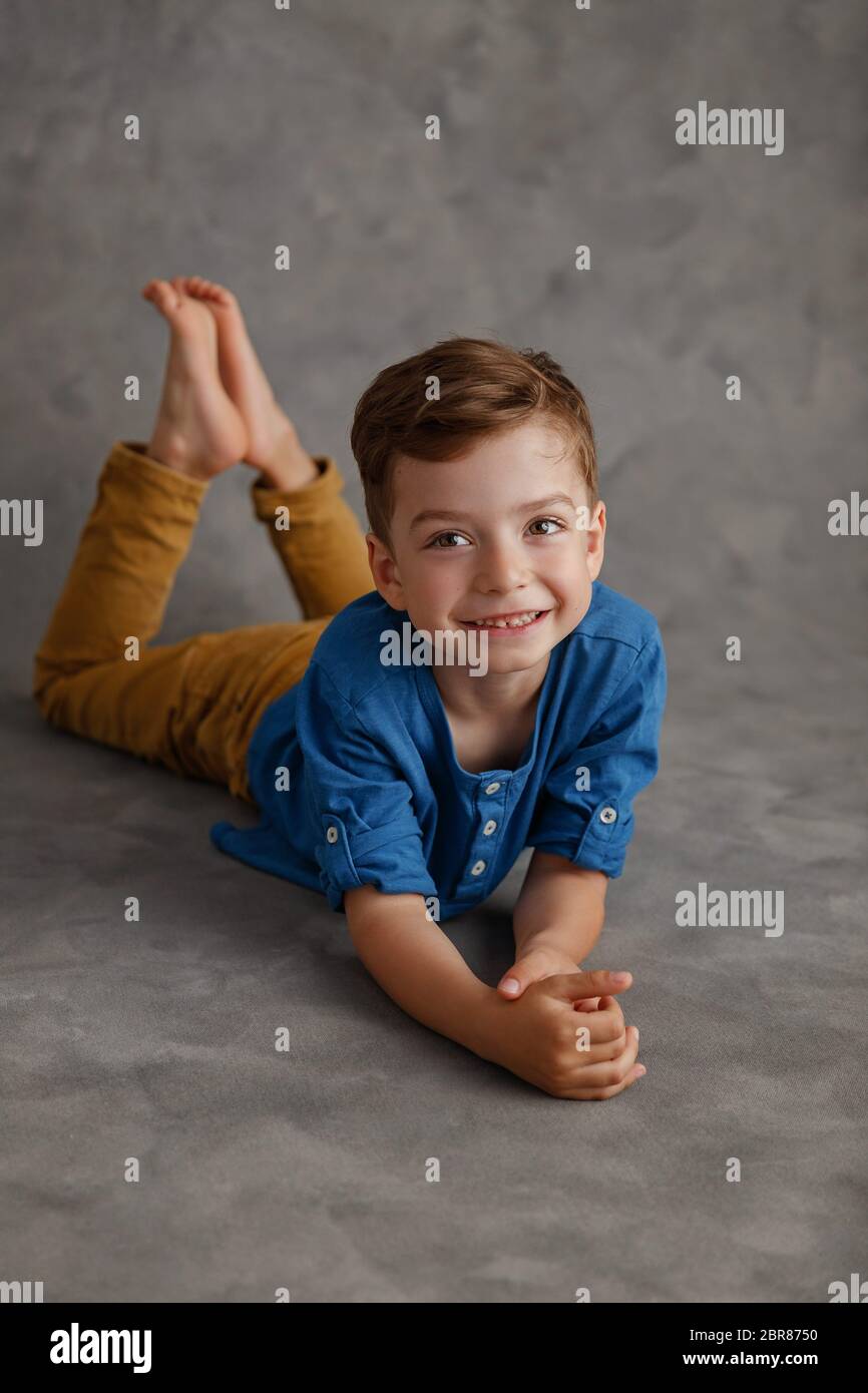 Garçon de 5 ans chemise bleue et pantalon jaune studio portrait sur fond  gris Photo Stock - Alamy