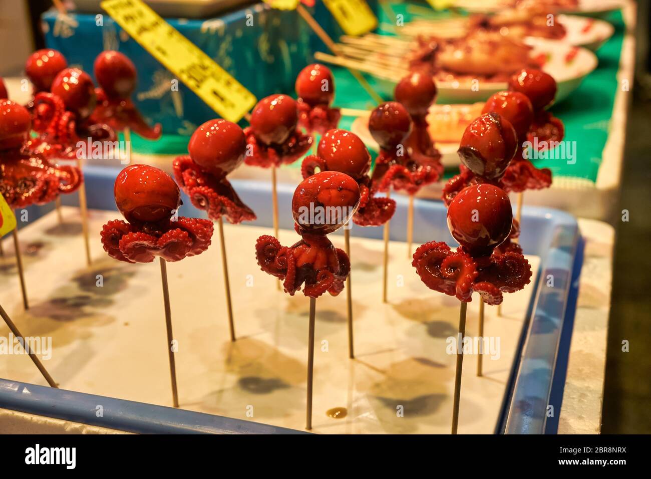 Poulpe rouge marinée sur un bâton exposé sur le comptoir au marché des fruits de mer de Kyoto. Cuisine de rue japonaise. Japon Banque D'Images