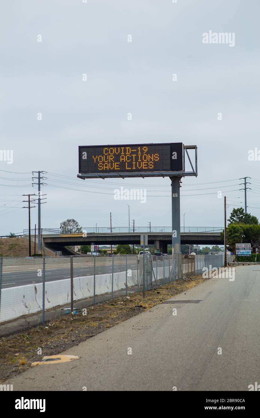 Le panneau Covid-19 du coronavirus sur l'autoroute 55 avertissant les automobilistes vos actions sauvent des vies. Direction sud sur l'autoroute 55 Orange County , Californie Banque D'Images
