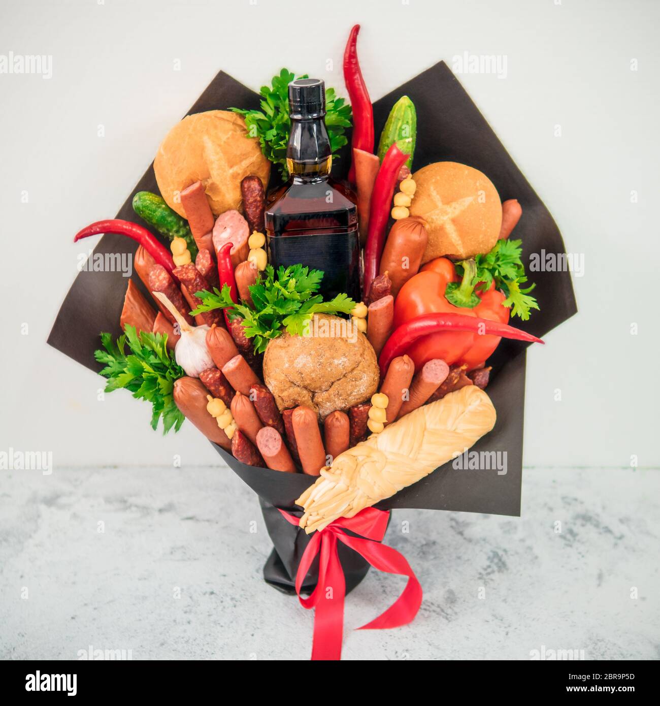 La viande et chese bouquet pour l'homme. Manger bouquet sur fond gris. Saucisses, légumes, fromage, pain et bouteille d'alcool fort en bouquet. G inhabituel Banque D'Images