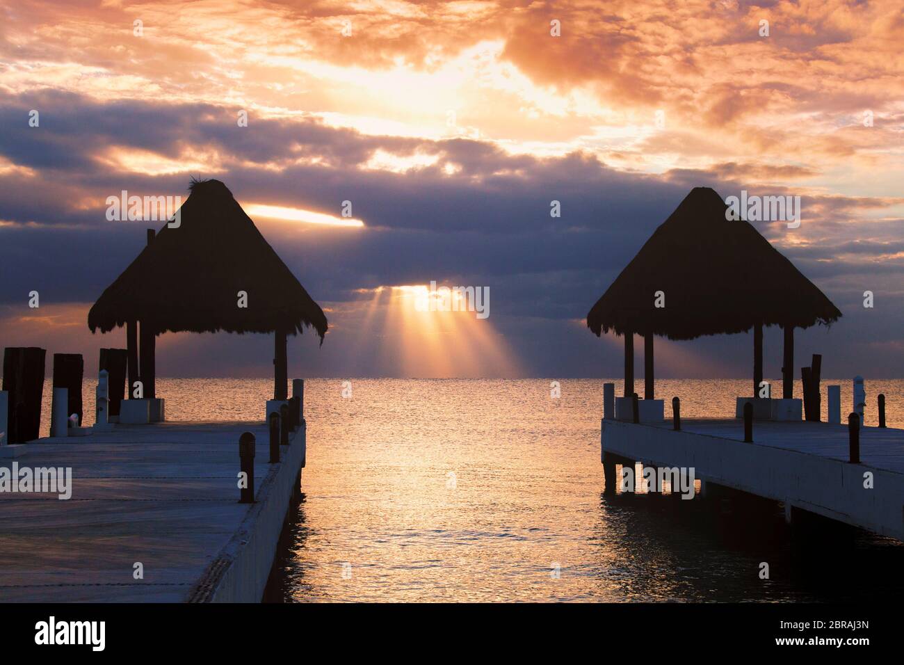 Les rayons du soleil traversent les nuages au lever du soleil à Puerto Morelos, Quintana Roo sur la Riviera Maya du Mexique. Banque D'Images