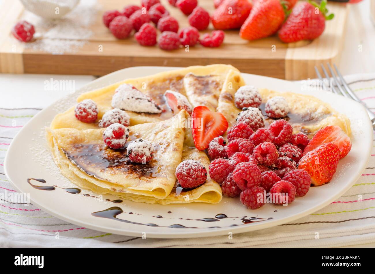 Des crêpes faites maison avec la réduction de vinaigre balsamique et de fruits frais, fraises et framboises Banque D'Images