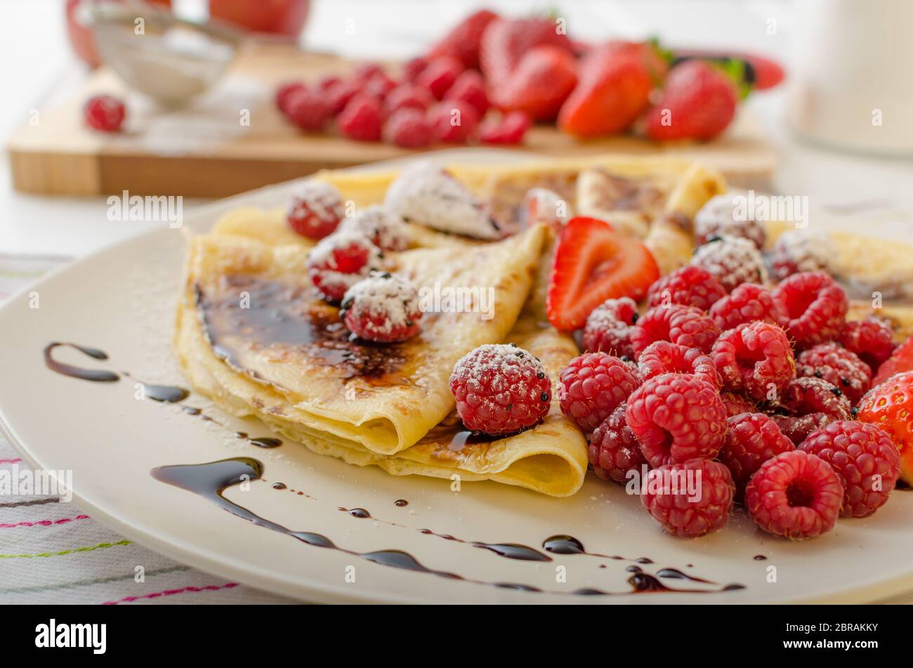 Des crêpes faites maison avec la réduction de vinaigre balsamique et de fruits frais, fraises et framboises Banque D'Images