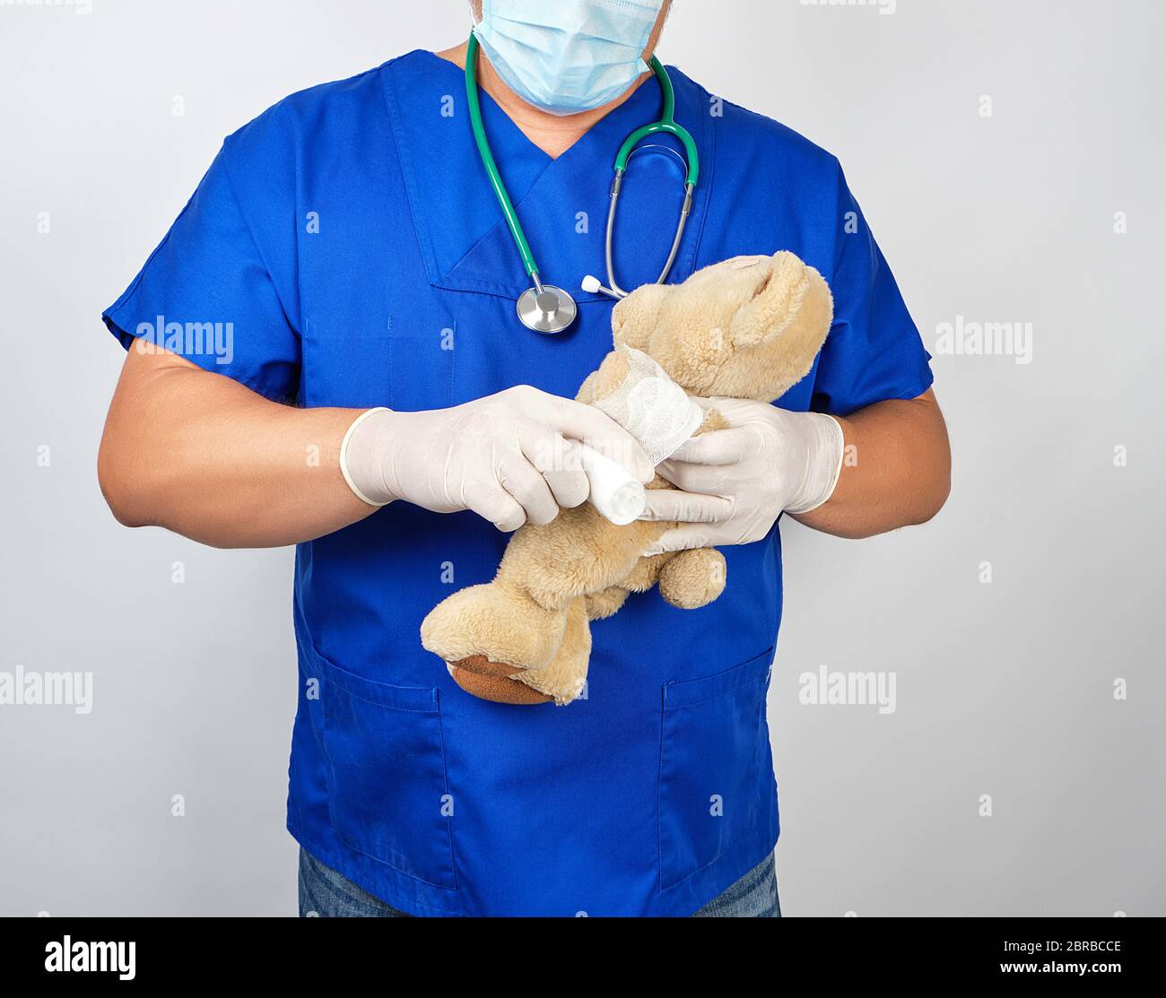 Médecin en uniforme bleu blanc bandages bandage médical paw ours en peluche brun, fond blanc Banque D'Images