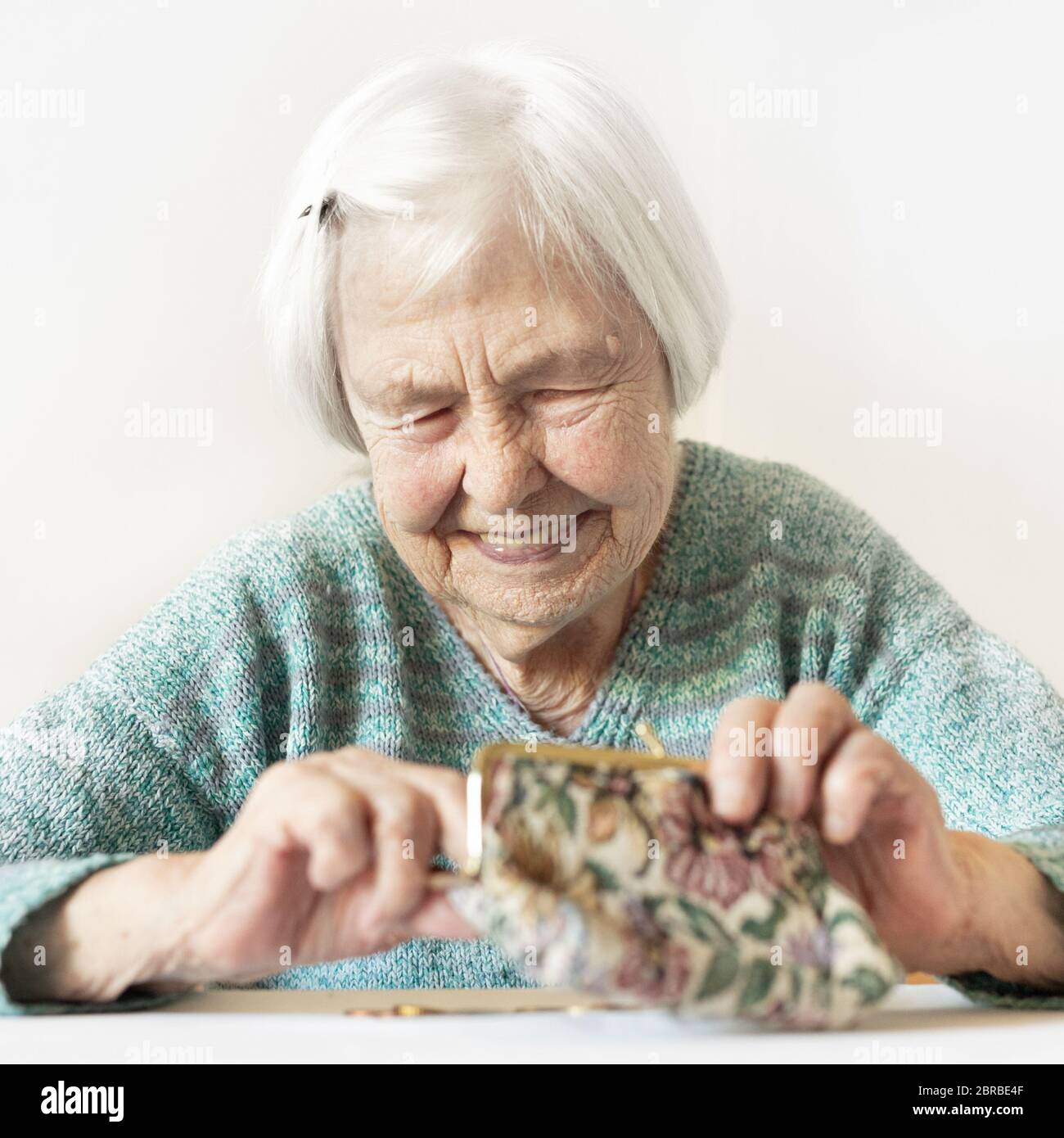 Personnes âgées gaies 96 ans woman sitting at table à la maison heureux avec elle dans son portefeuille d'épargne-retraite après le paiement des factures. L'épargne-retraite un Banque D'Images