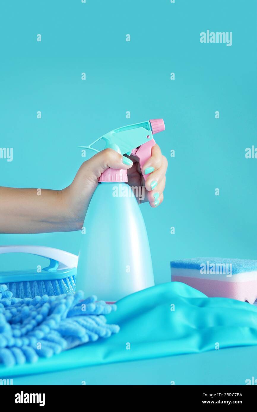 femme tenant main spray nettoyant plastique bleu bouteille détergent isolé sur fond bleu avec outils de nettoyage fournitures de produit Banque D'Images