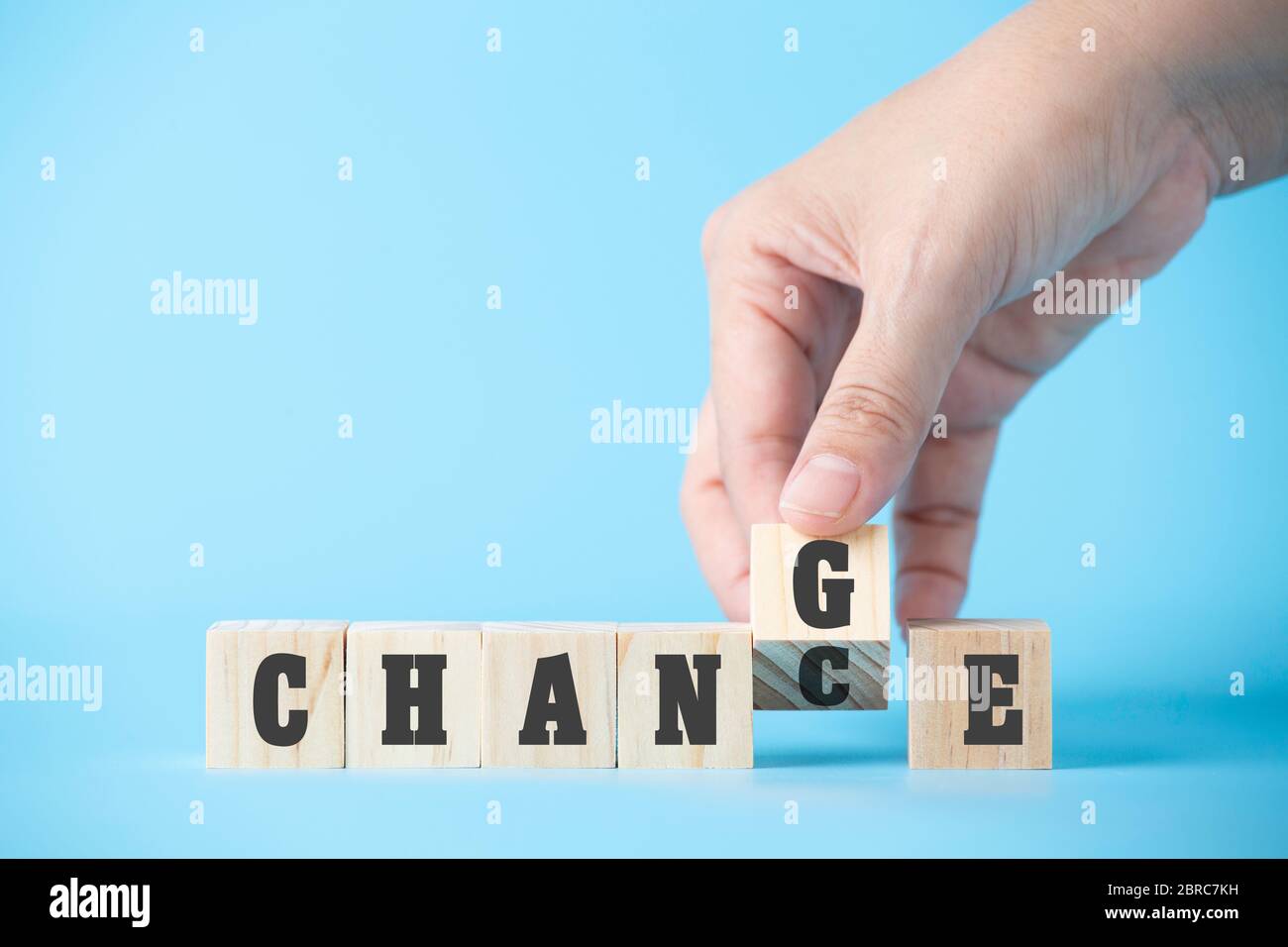 Femme main tenir le mot de cube en bois sur l'arrière-plan bleu d'affaires concept pour le changement mentalité à la construction de l'organisation croissance dans le succès, chance de solution Banque D'Images