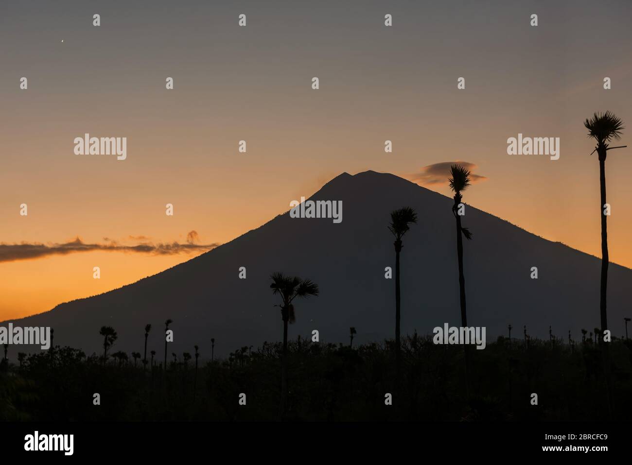 Coucher de soleil orange au-dessus du volcan Agung, île de Bali. Vue sur le volcan depuis la plage de sable noir au crépuscule, Indonésie. Banque D'Images