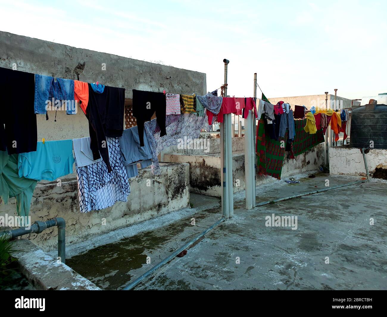 Les vêtements sont mis au sec sur les cordes à la toiture du bâtiment - les vêtements suspendus attendant la disparité de soleil Banque D'Images