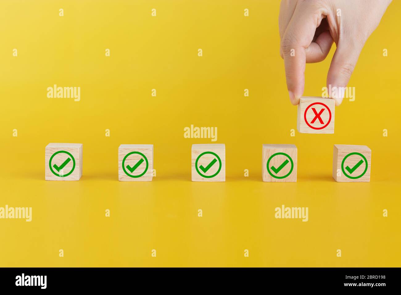 Les doigts ramassent le cube en bois avec la marque X relevée pour créer l'espace entre eux. Distance sociale ou distance physique pour le nouveau concept normal. Banque D'Images