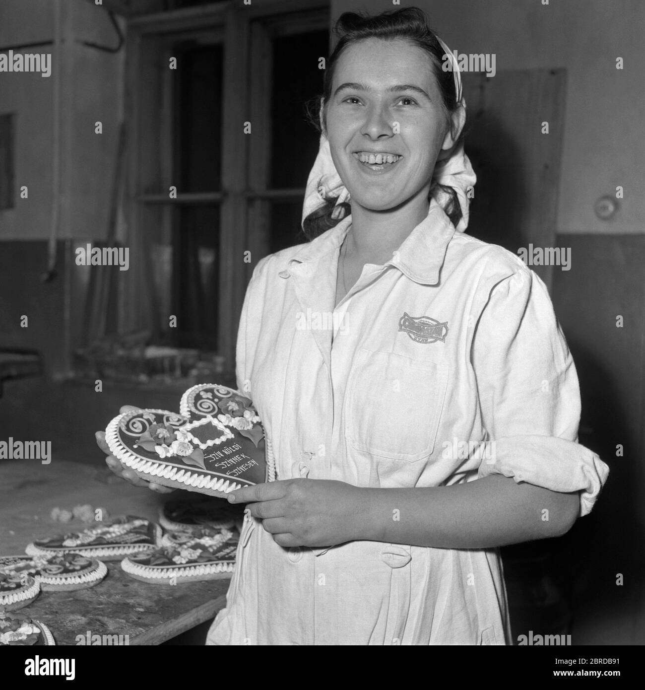 femme souriante de boulangerie tenant le pain d'épice en forme de coeur années 1950 hongrie Banque D'Images