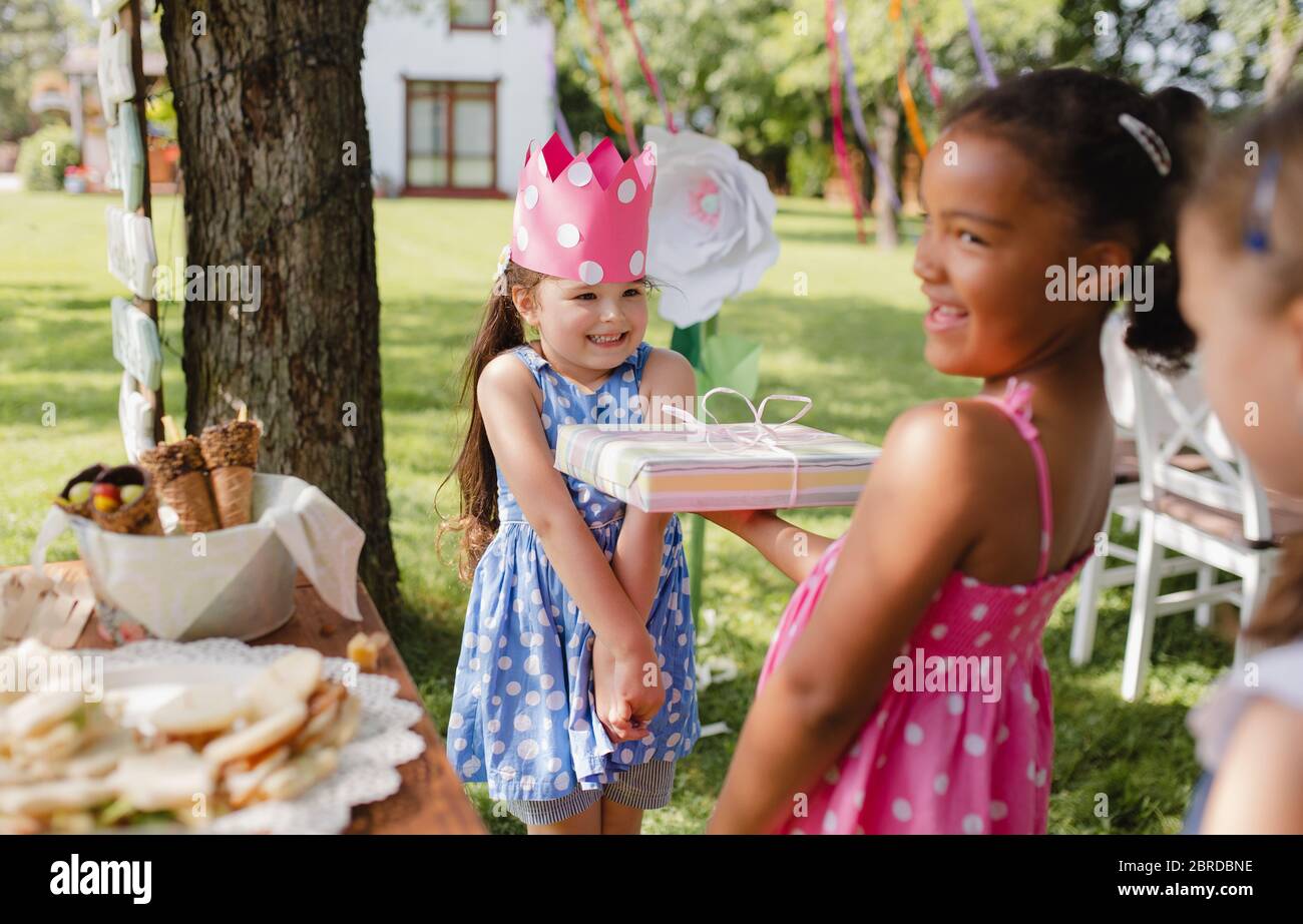 Portrait de petite fille avec des amis et présente à l'extérieur dans le jardin en été. Banque D'Images