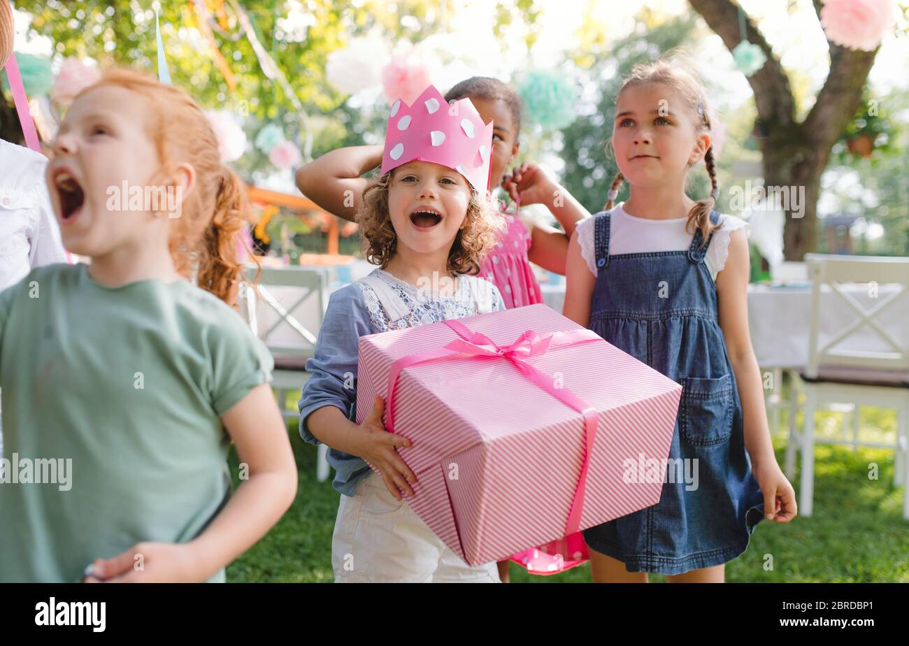 Portrait de petite fille avec des amis et présenter à l'extérieur dans le jardin en été. Banque D'Images