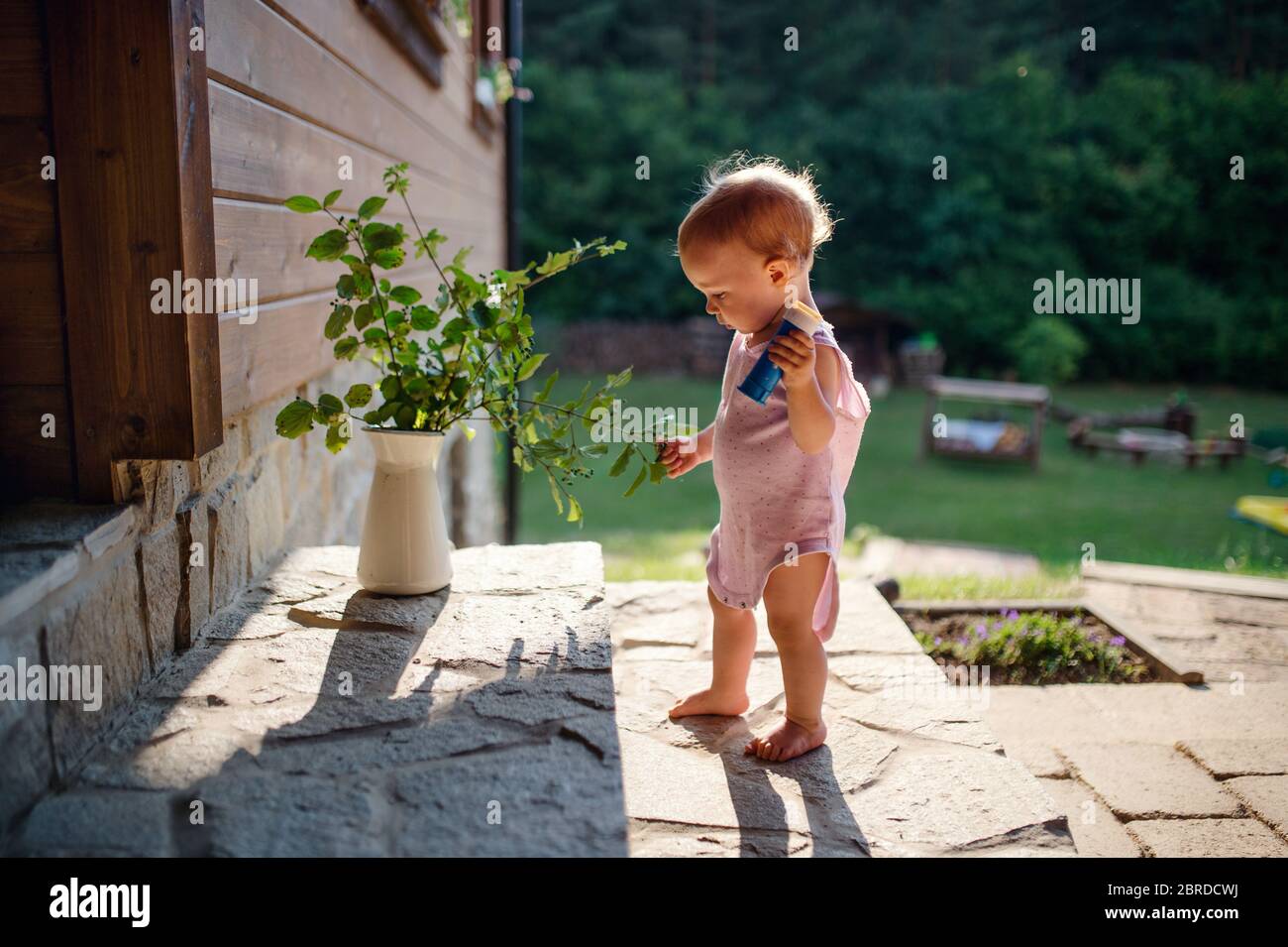 Une adorable petite fille debout devant la maison en été. Banque D'Images