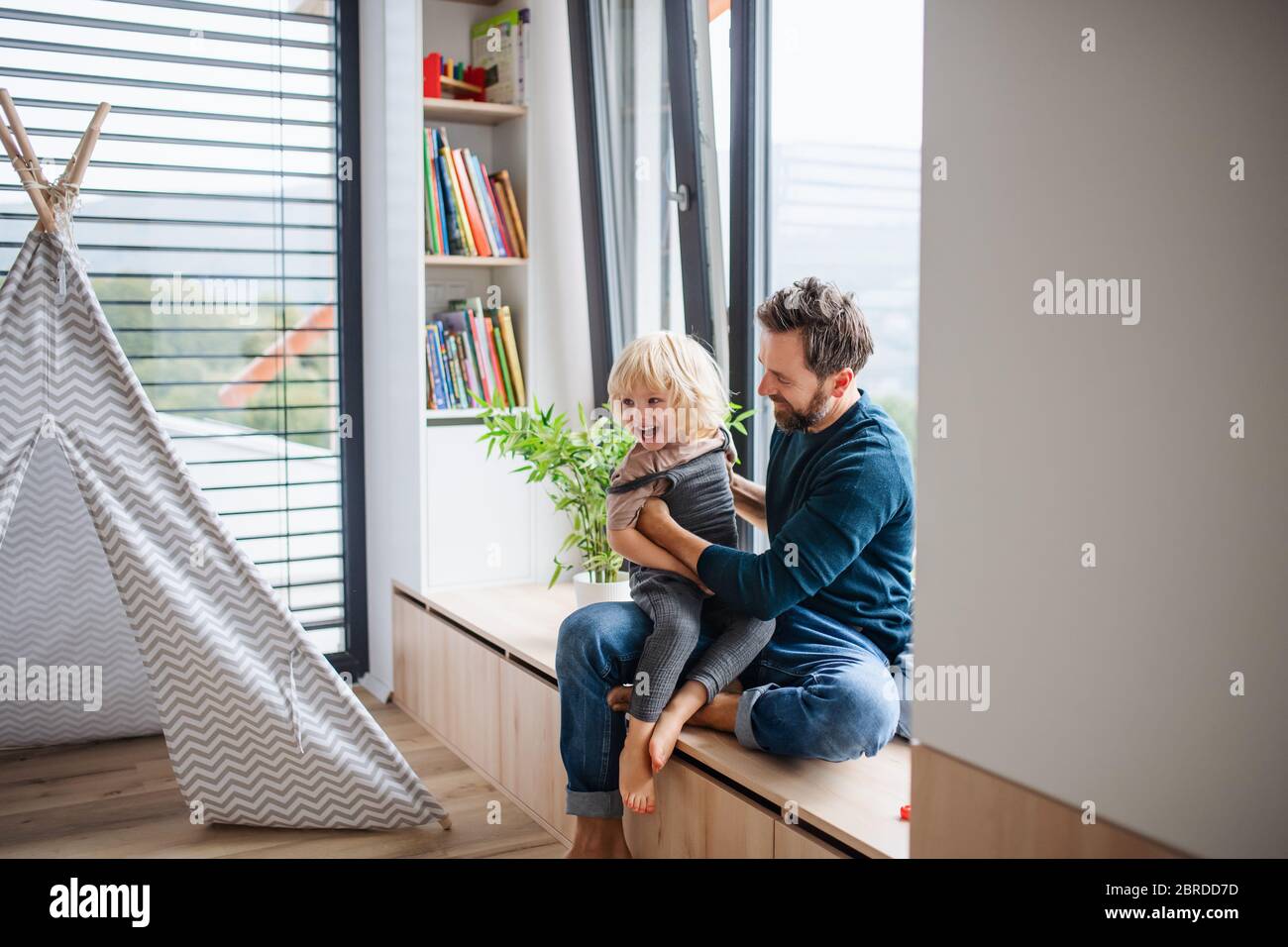 Père avec un petit garçon jouant à l'intérieur dans la chambre, jouant. Banque D'Images