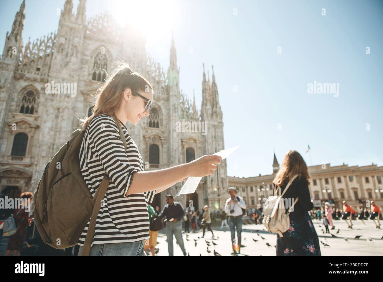 Girl touriste ou étudiant avec un sac à dos ressemble à la carte. Dans l'arrière-plan la cathédrale Duomo de Milan en Italie et méconnaissable. Banque D'Images