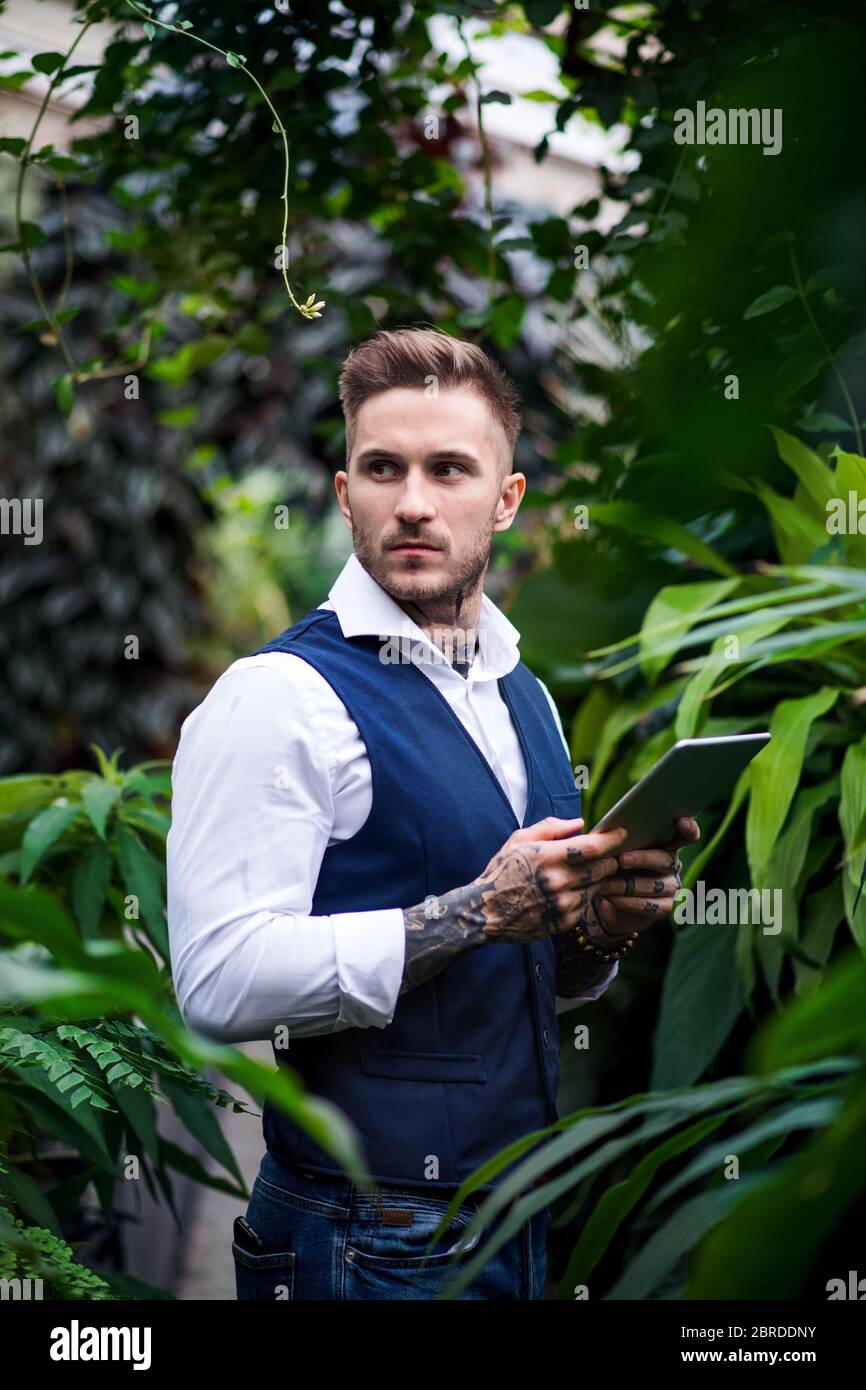 Jeune homme avec une tablette dans le jardin botanique. Banque D'Images