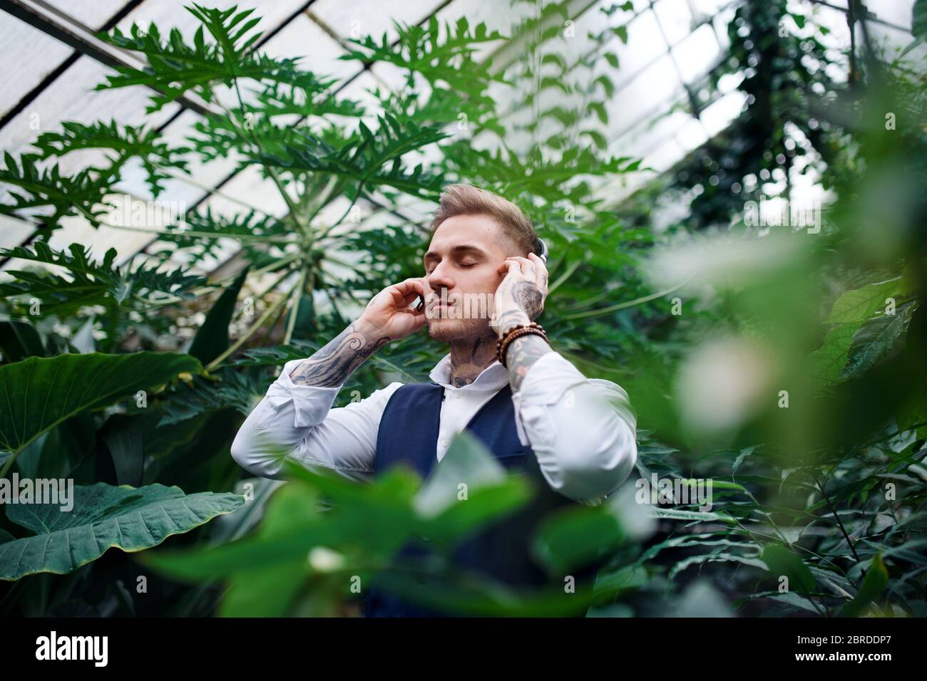 Jeune homme avec casque dans le jardin botanique. Banque D'Images