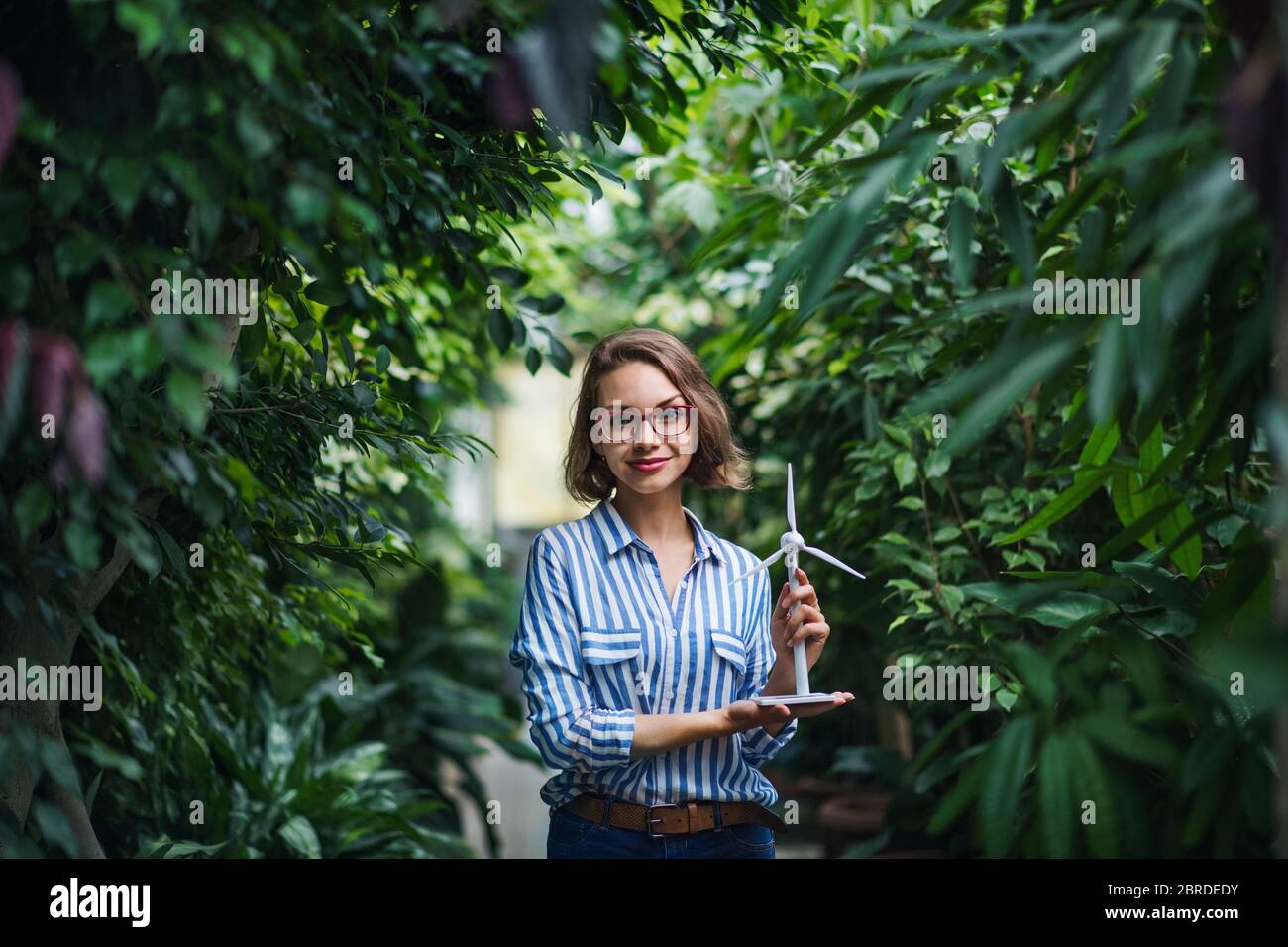 Jeune femme avec modèle de moulin à vent debout dans le jardin botanique. Banque D'Images