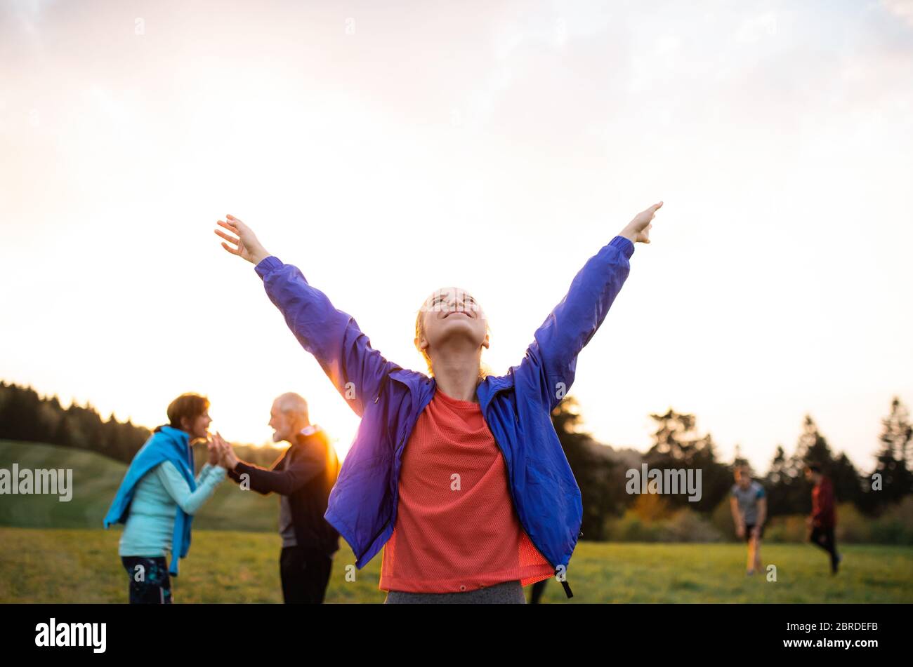 Un portrait de jeune femme avec un grand groupe de personnes faisant de l'exercice dans la nature. Banque D'Images