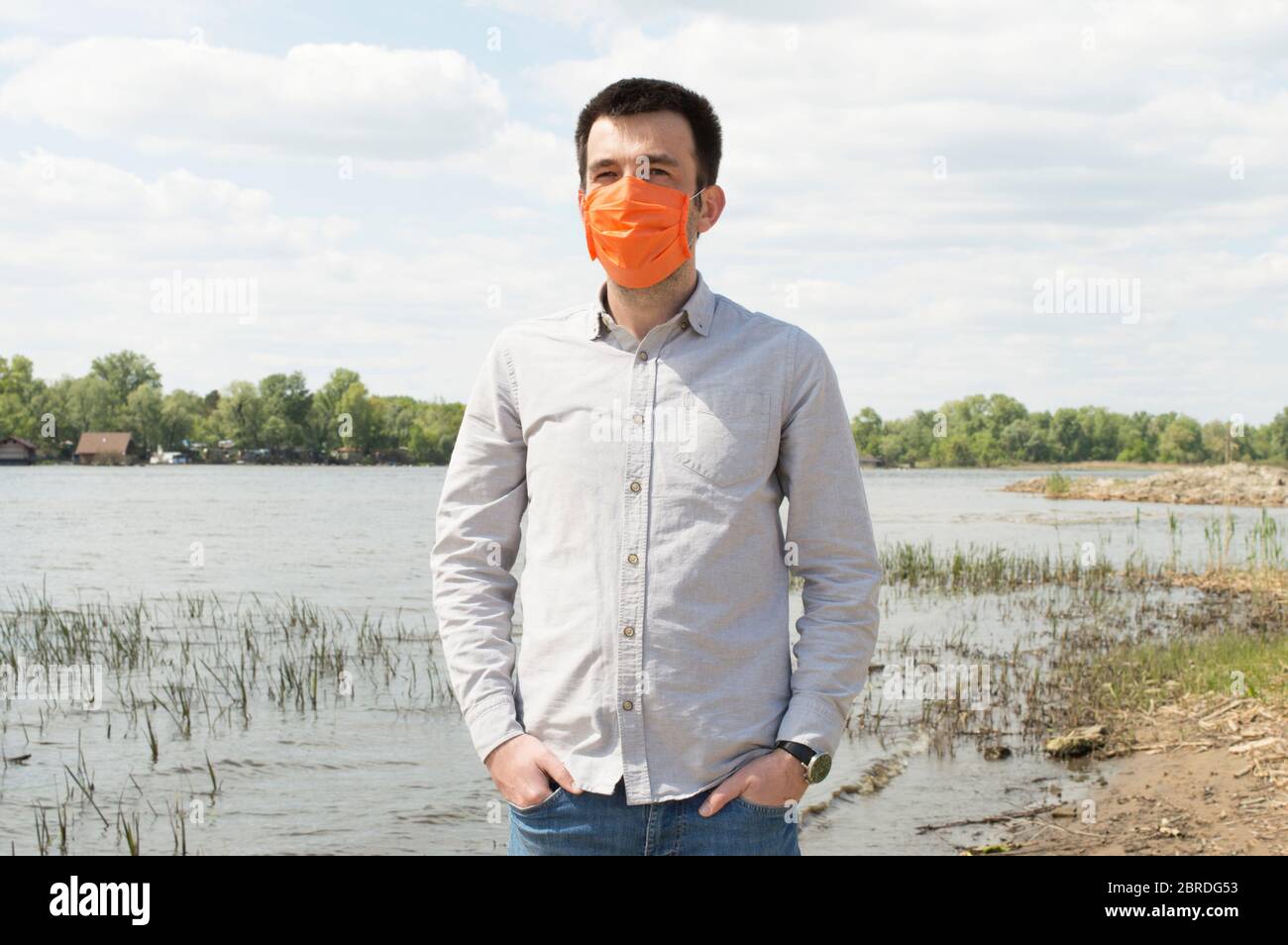 Turc en chemise gris clair et masque orange vif sur la rive du Dnieper à Kiev, Ukraine. Concepts de protection des soins de santé pendant Banque D'Images