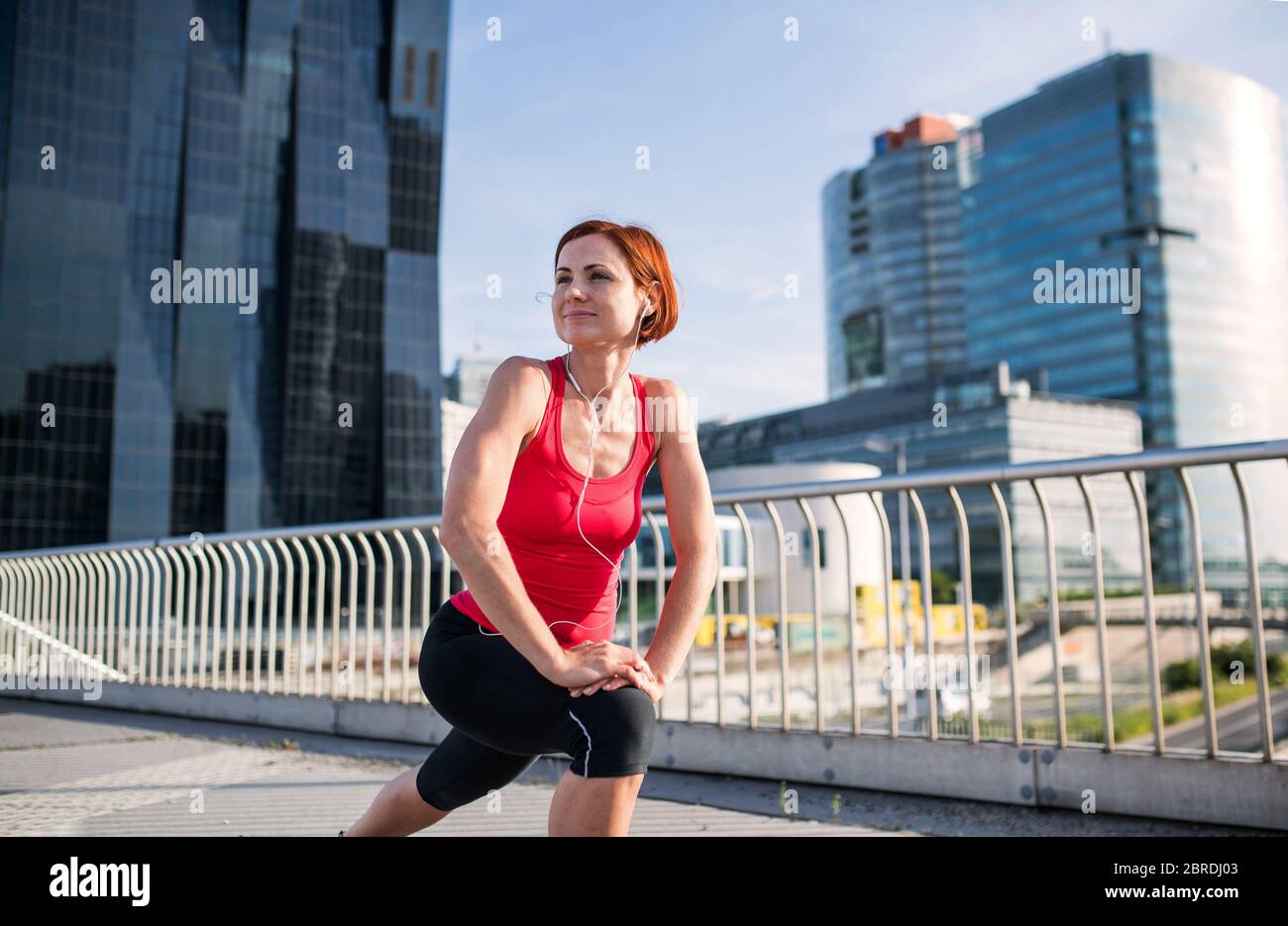 Jeune femme faisant de l'exercice sur le pont extérieur dans la ville, s'étirant. Banque D'Images