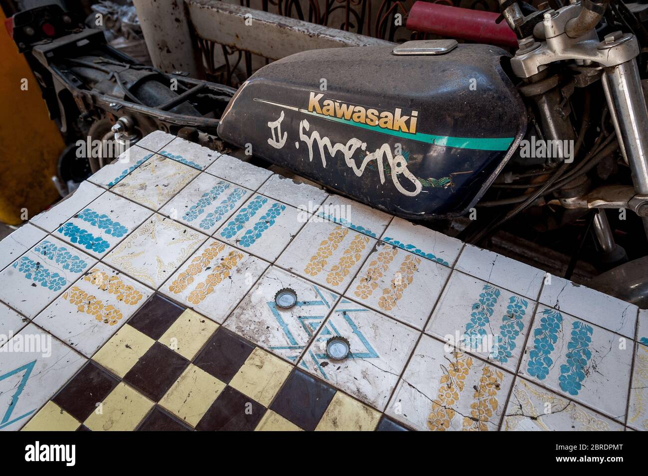 Une vieille moto se trouve à côté d'une table utilisée comme planche à brouillons dans une zone pauvre de Bangkok Thaïlande. Banque D'Images