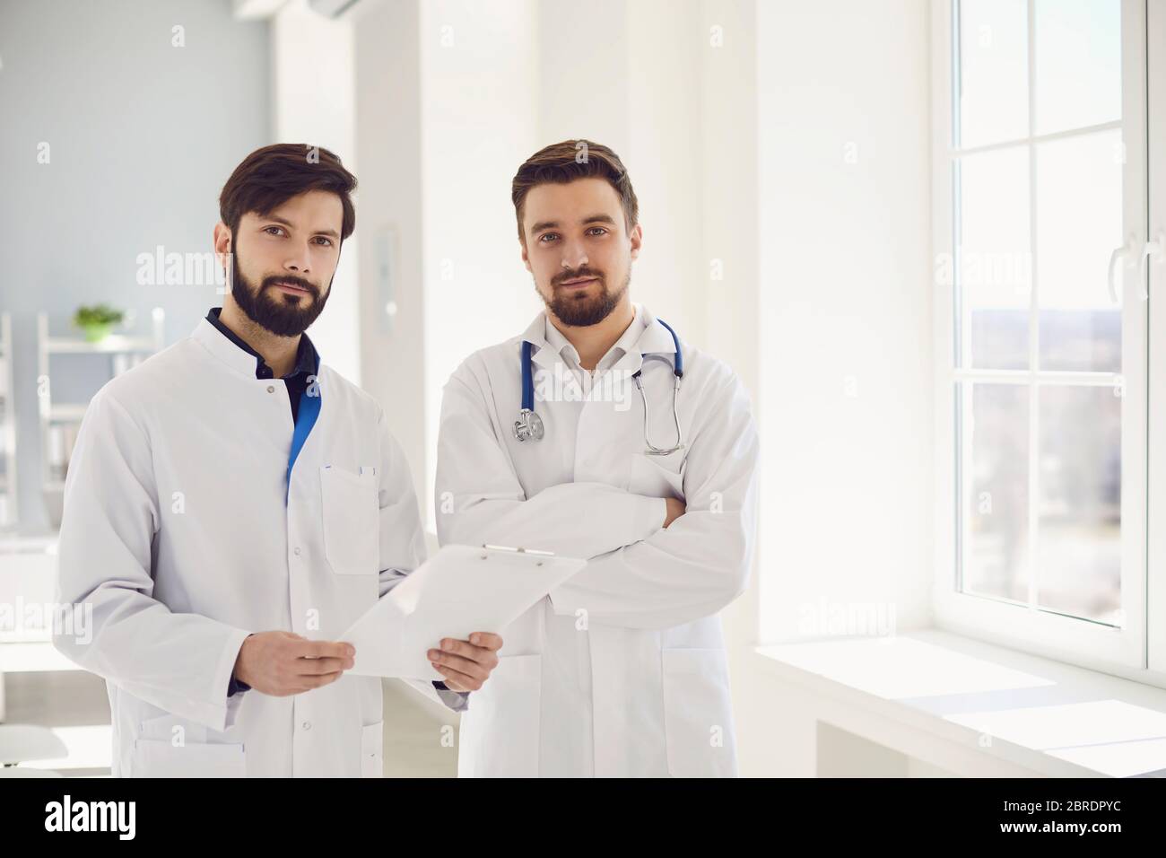 Deux médecins praticiens avec un presse-papiers debout dans un bureau de clinique.médecine de soins de santé.les travailleurs médicaux attendent les patients sur le lieu de travail. Ajuster Banque D'Images
