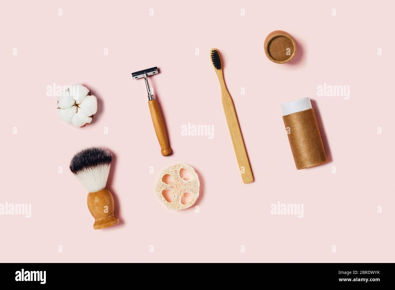 Accessoires de salle de bains sur fond rose. Brosse à dents en bambou naturel, éponges, fleurs en coton, brosse à rasage. Flat lay, vue de dessus. Banque D'Images
