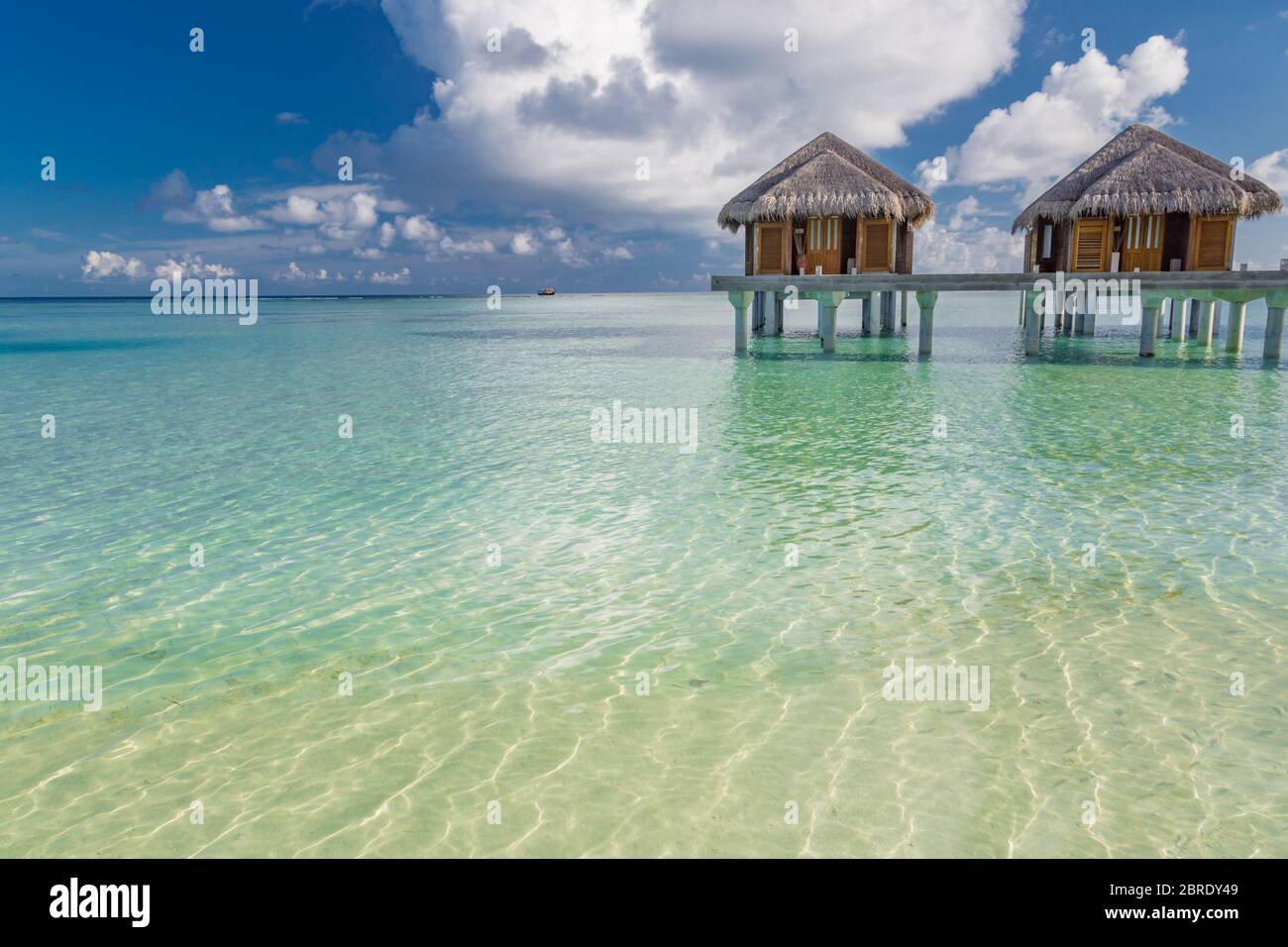 Plage tropicale aux Maldives avec luxe sur l'eau bungalows ou villas. Superbe lagon avec ciel bleu et nuages. Destination exotique Banque D'Images