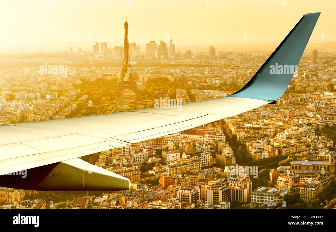 L'avion survole Paris en soirée d'été, en France. Vue panoramique aérienne de la tour Eiffel depuis la fenêtre de l'avion. L'aile de l'avion au-dessus des rues de Paris Banque D'Images