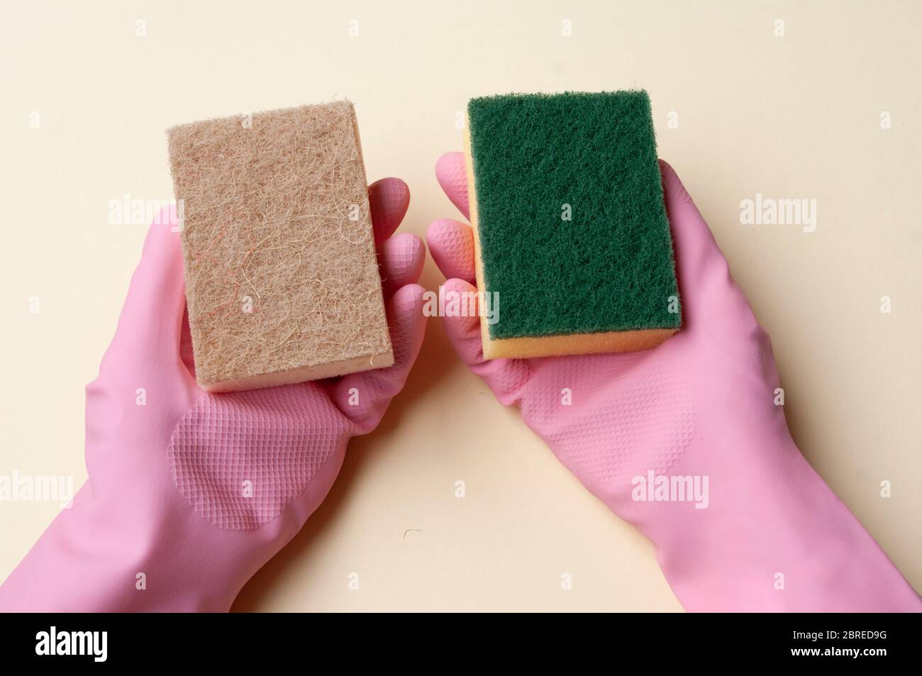 Mains dans des gants en caoutchouc tenant des éponges diffrentes. Éponge en plastique et naturelle. Banque D'Images