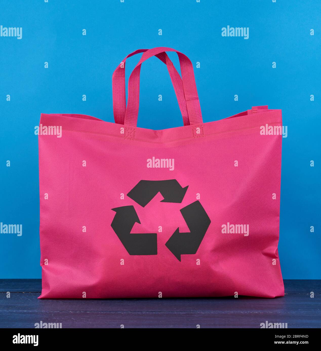 Sac en viscose rose entièrement réutilisable sur fond en bois bleu, concept de réduction des déchets en plastique Banque D'Images