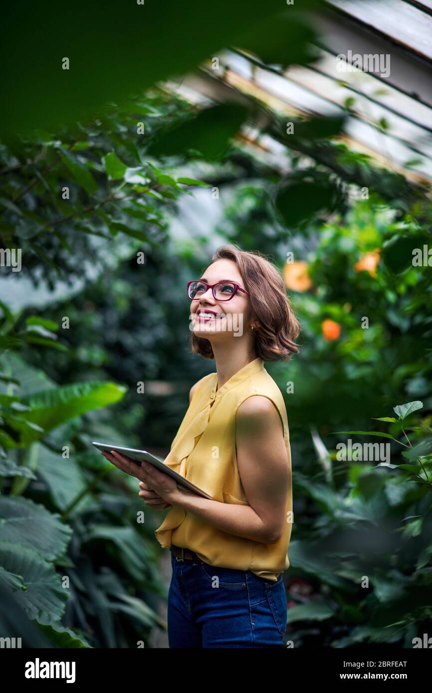 Jeune femme avec une tablette dans le jardin botanique. Copier l'espace. Banque D'Images