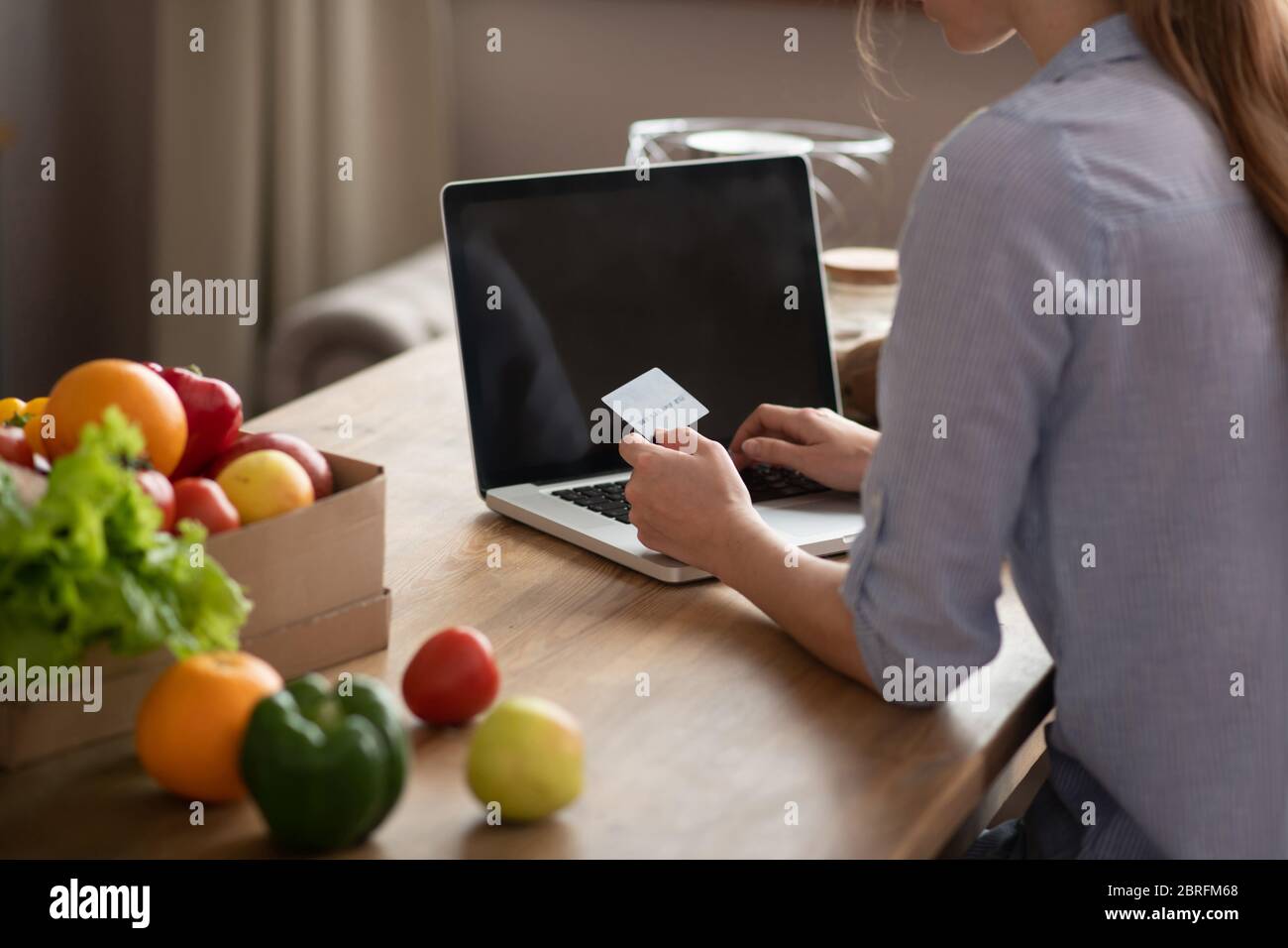 Fille en homowear grise tenant une carte de crédit dans sa main et payant en ligne Banque D'Images