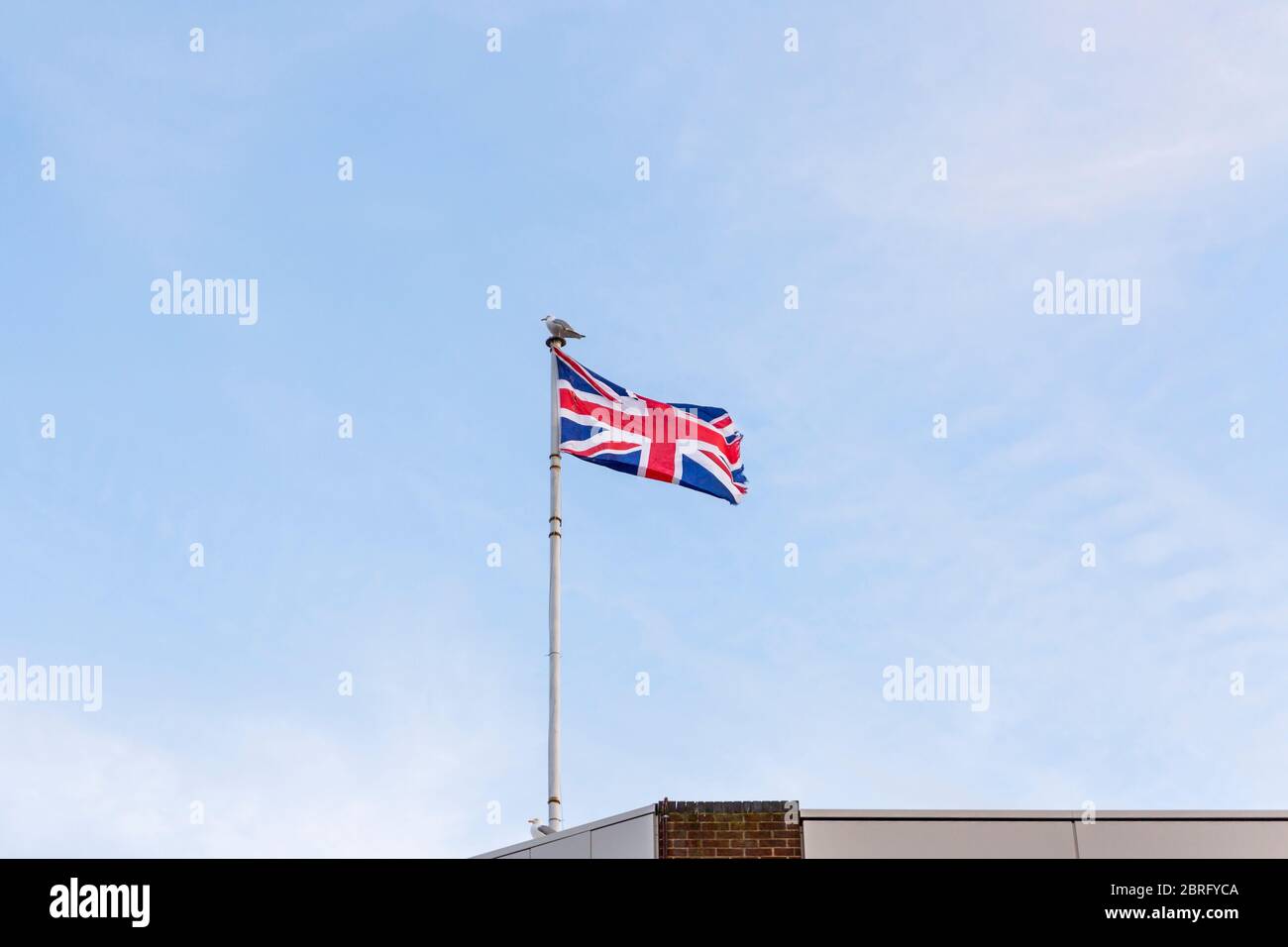 Drapeau du Royaume-Uni, drapeau d'Angleterre brodé sur le ciel bleu sur le toit d'un bâtiment. Banque D'Images