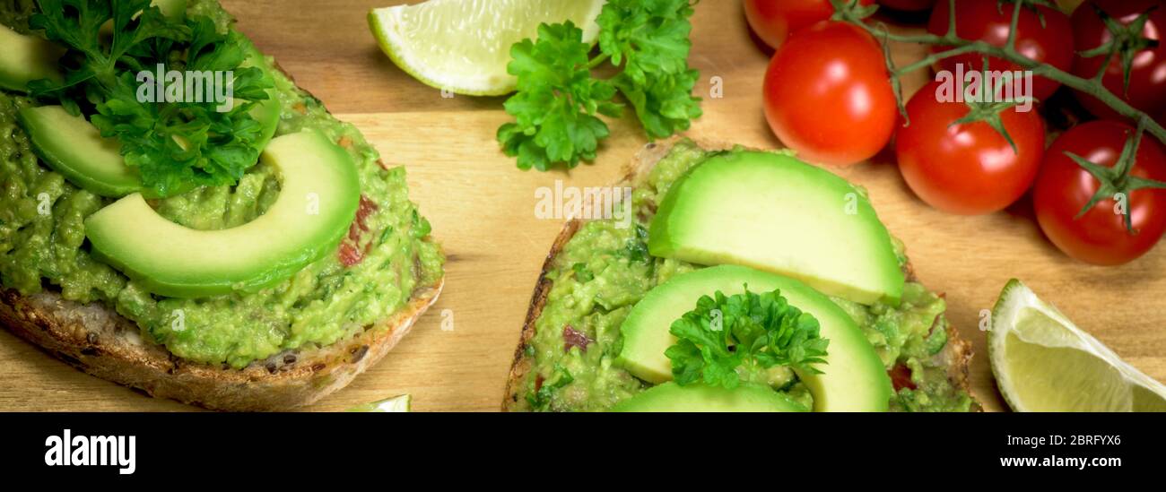 Tranche de pain avec guacamole à base d'avocat, de tomate, de lime, de poarsley et d'ail - gros plan - bannière Banque D'Images