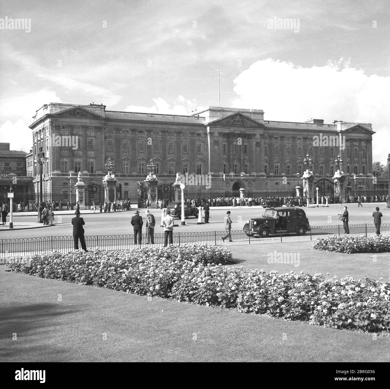 Années 1950, historique, les gens dehors regardant par les portes de Buckingham Palace, Westminster, Londres, Angleterre, Royaume-Uni. Ouvert en 1705, le palais est la résidence et le siège administratif de la monarchie britannique, la reine Elizabeth II Banque D'Images