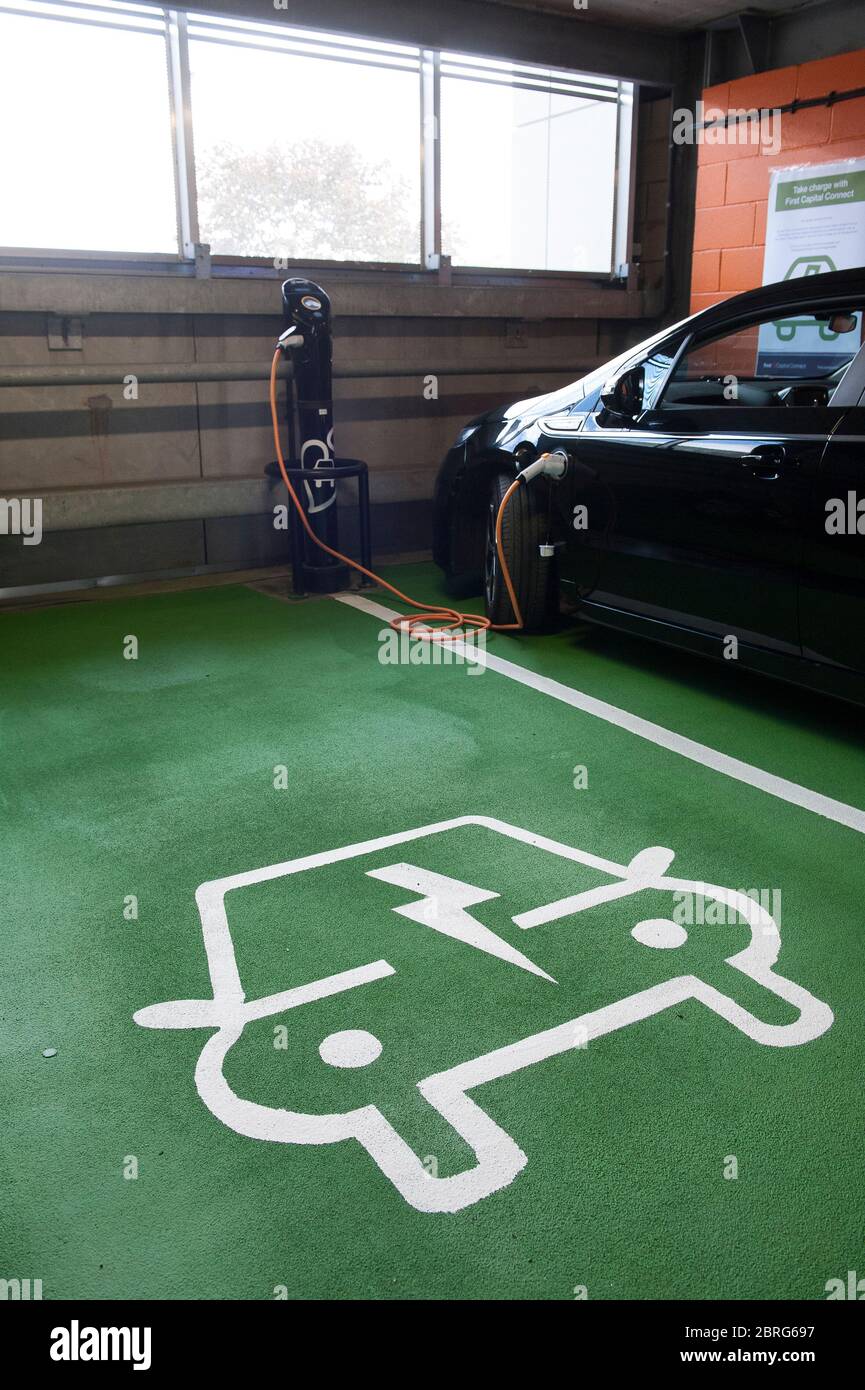 Utiliser un point de recharge de voiture électrique à une gare pour charger une voiture Vauxhall Ampera. Banque D'Images