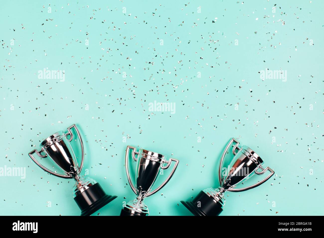 Coupes gagnant argent avec des sparkles sur fond menthe avec espace de copie. Concept festif. Style de pose à plat. Banque D'Images