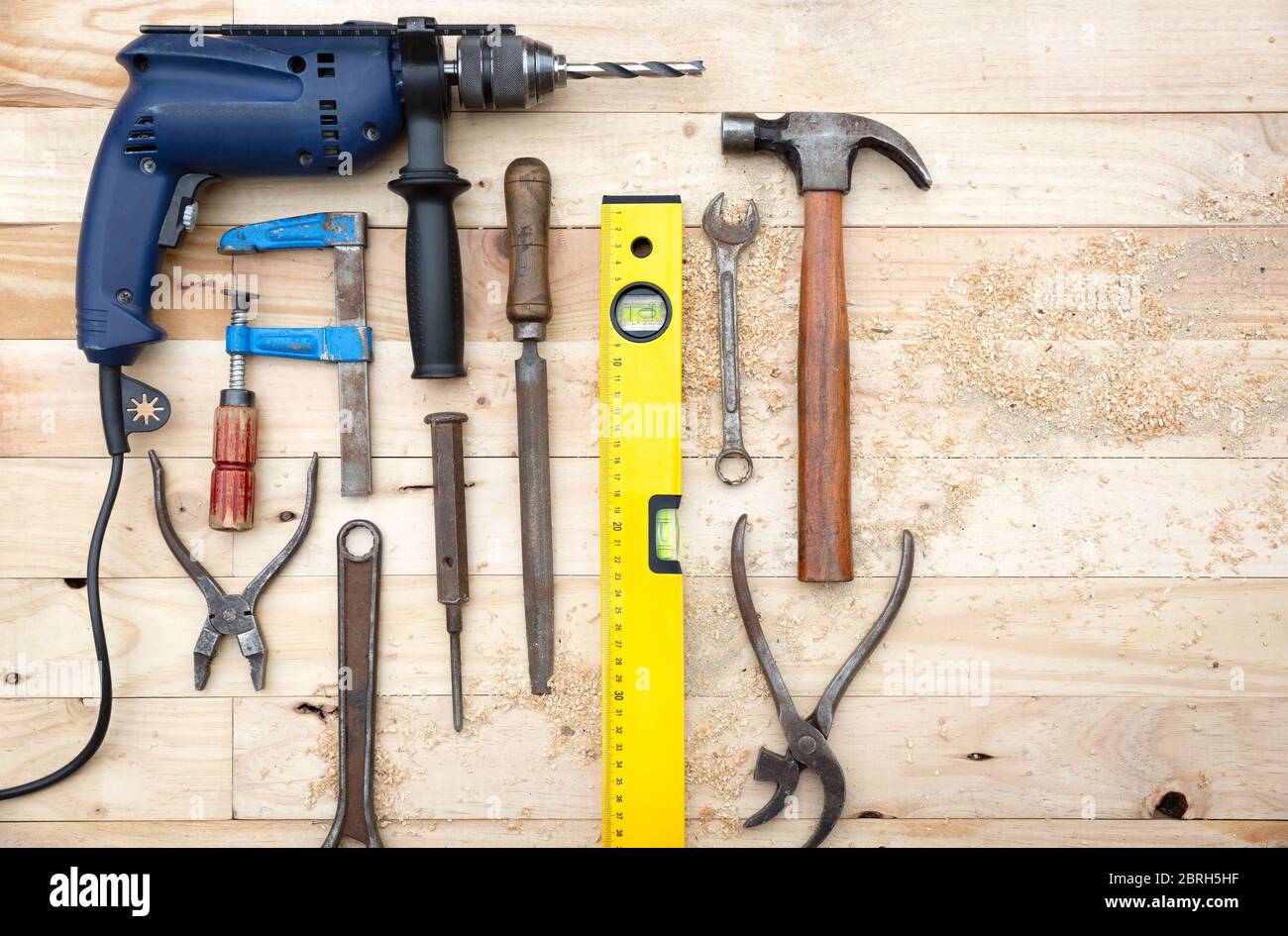 Vue du dessus ensemble d'outils comprenant un foret, un marteau et d'autres accessoires de menuiserie placés sur un établi en pin naturel. Concept de travail et de bricolage. Banque D'Images