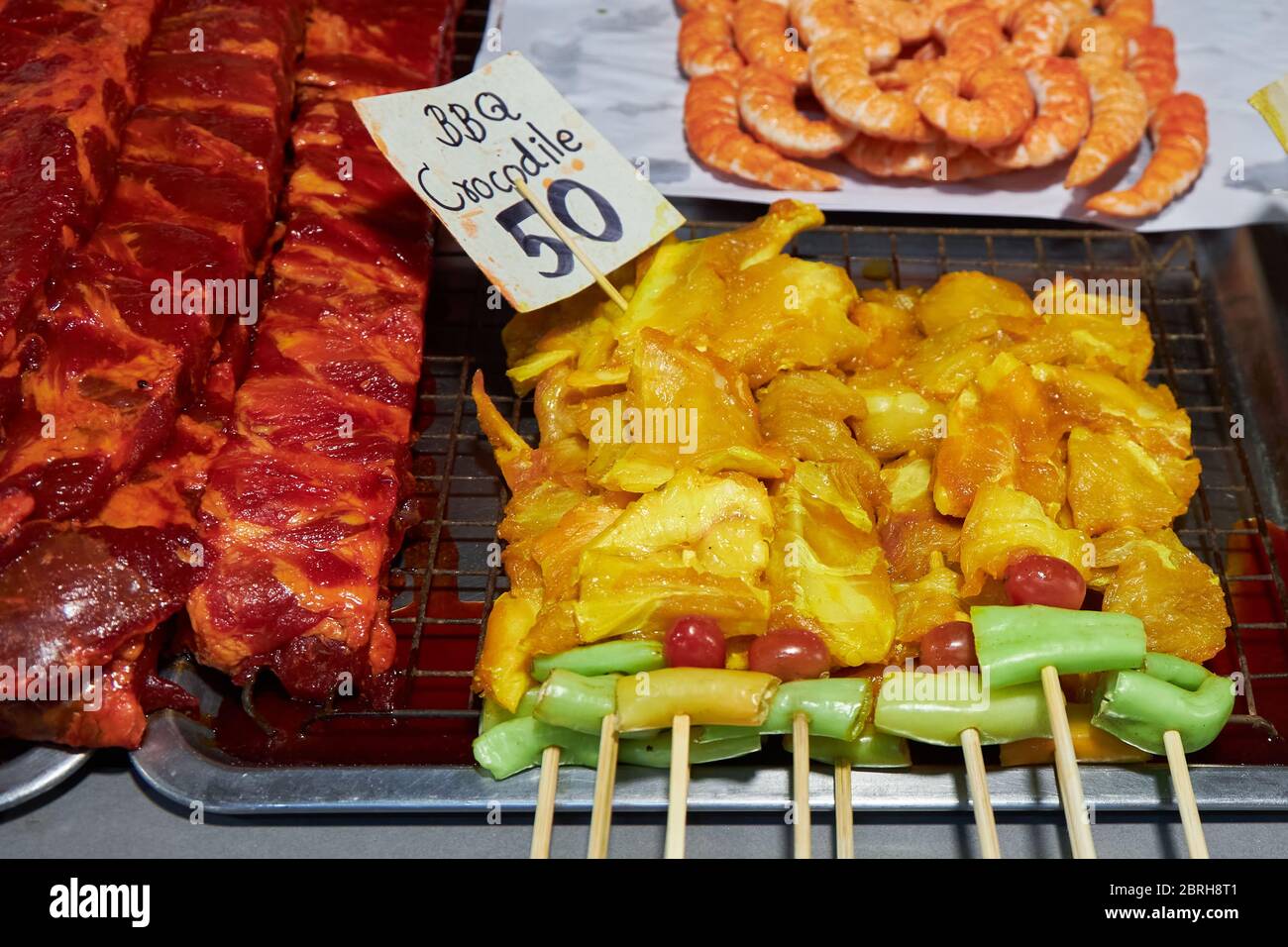 Des bâtons de barbecue avec de la viande de crocodile se trouvent sur un comptoir dans un marché en Thaïlande. Banque D'Images