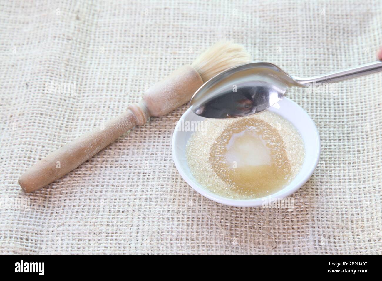 Faire une pâte de sirop de sucre en ajoutant de l'eau à non raffiné Sucre granulé pour le brossage sur les petits pains - Sally Série d'images Lunn Baking Banque D'Images