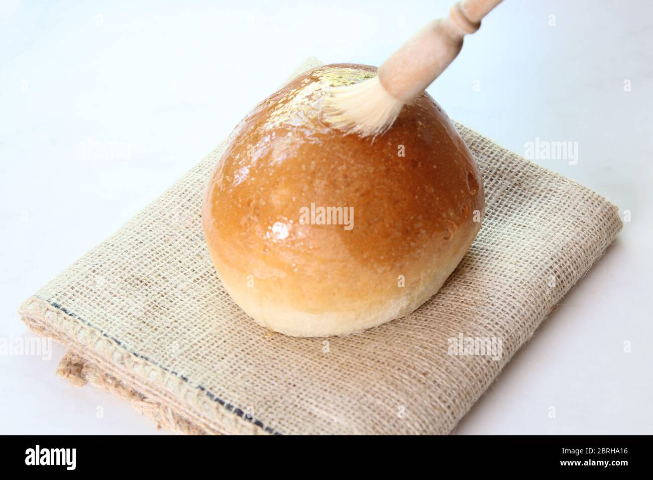 Glacer un pain frais de Sally Lunn avec de la pâte de sucre, brossant le dessus avec du sirop - Sally Lunn Baking série d'images Banque D'Images