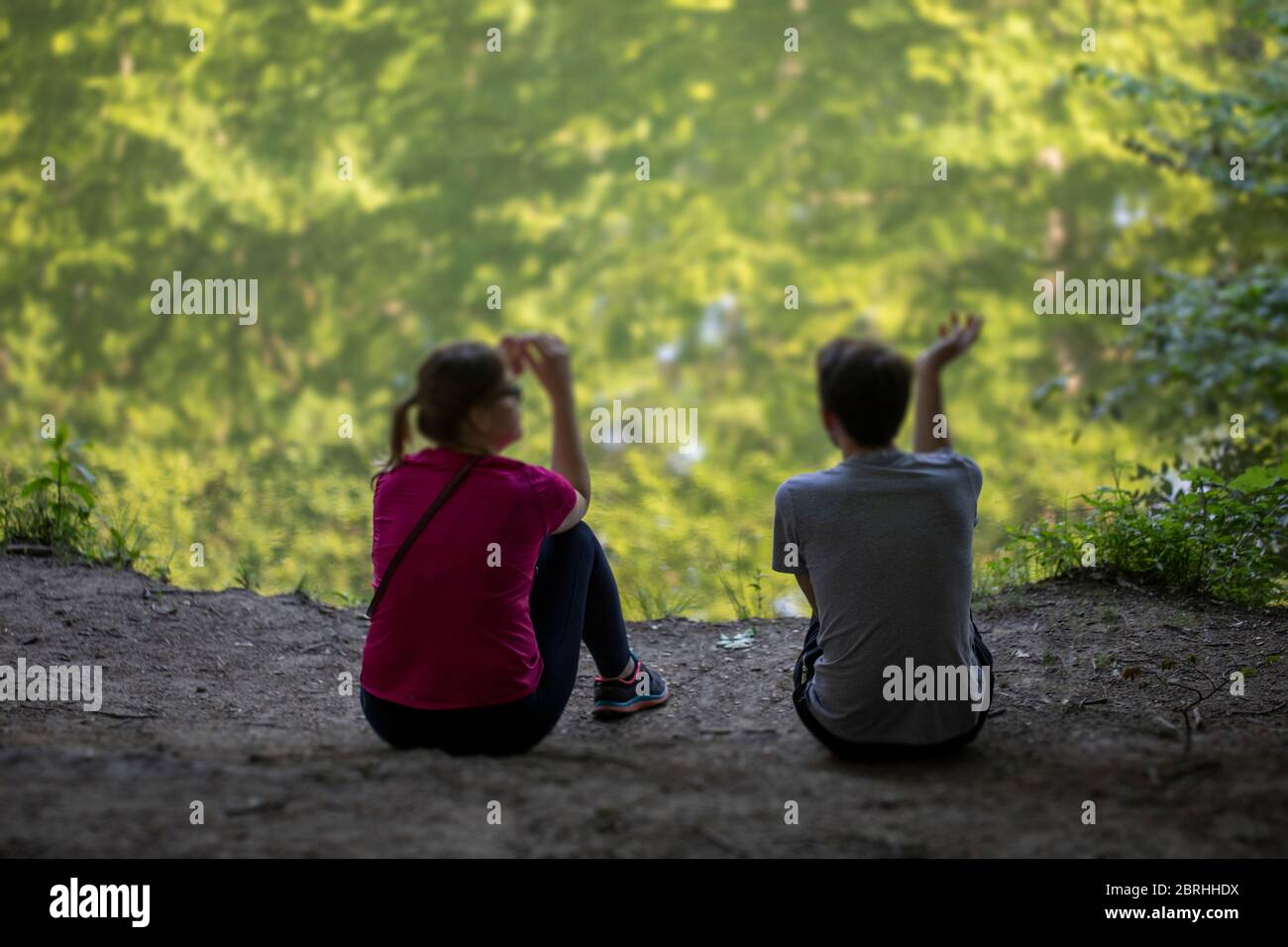 Deux personnes assises à côté d'un lac et parlant Banque D'Images