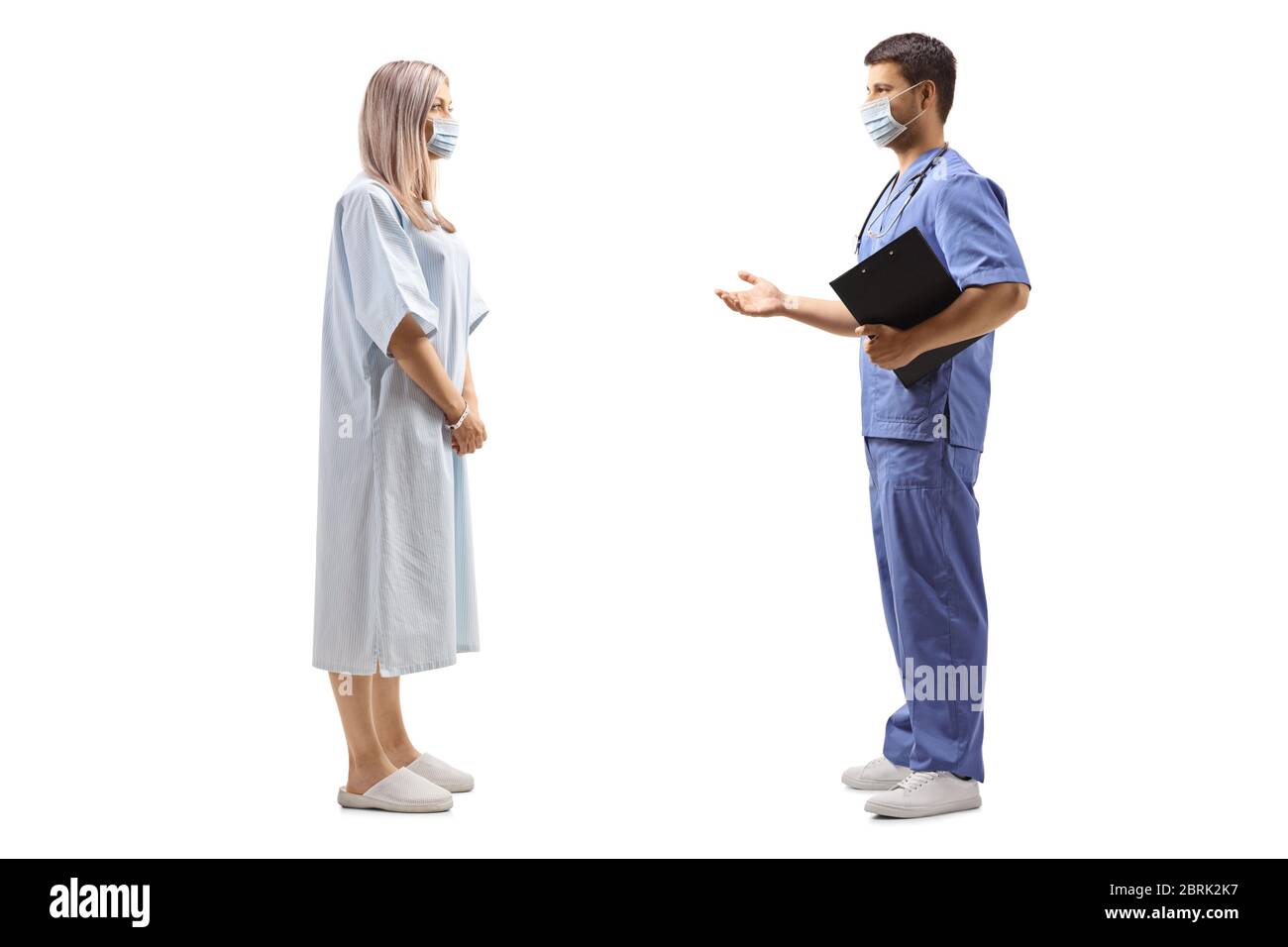 Prise de vue en profil d'une patiente dans une blouse d'hôpital et d'un médecin portant des masques protecteurs isolés sur fond blanc Banque D'Images