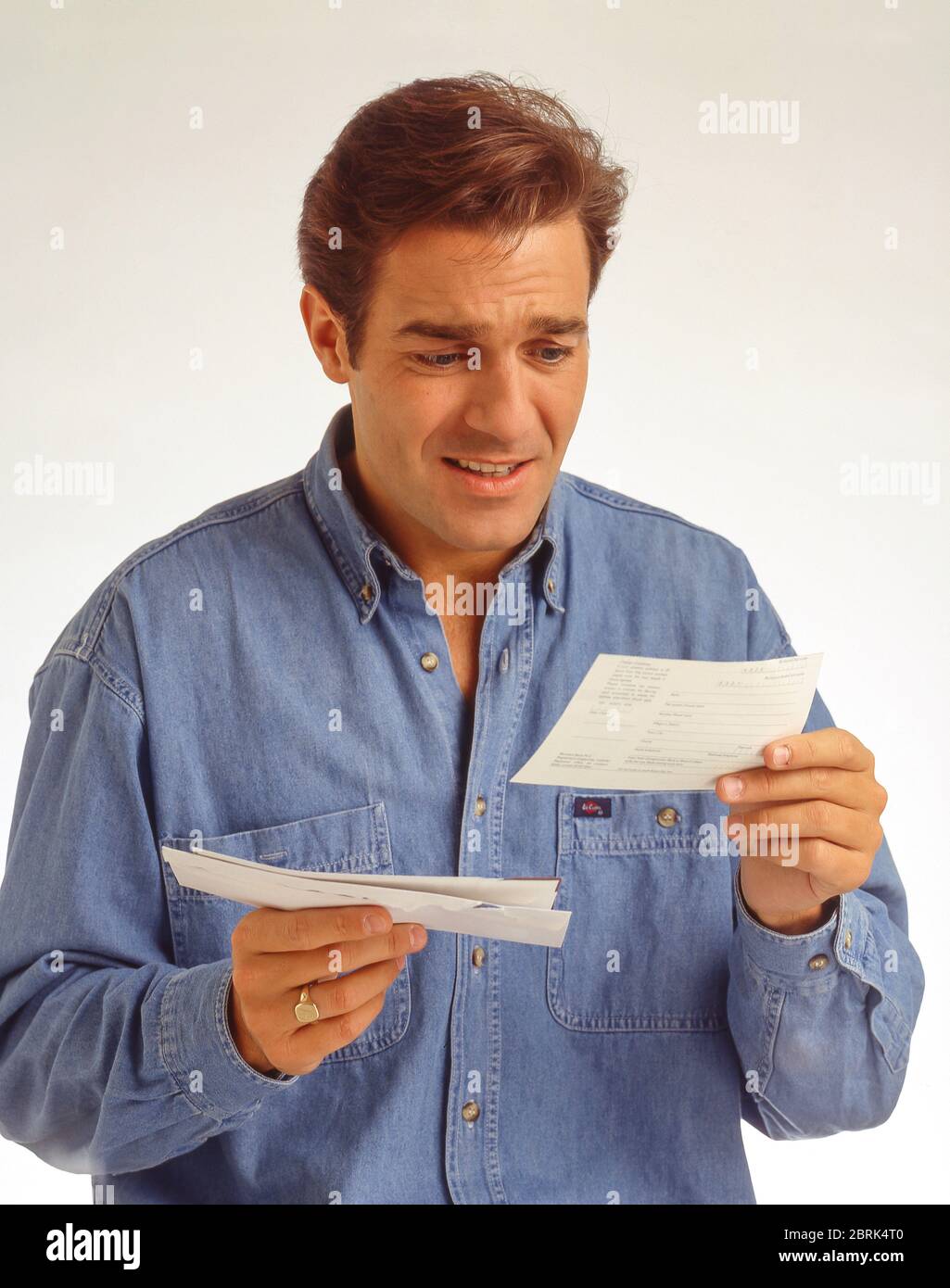 Jeune homme qui a l'air inquiet lorsqu'il reçoit une facture de ménage, Berkshire, Angleterre, Royaume-Uni Banque D'Images