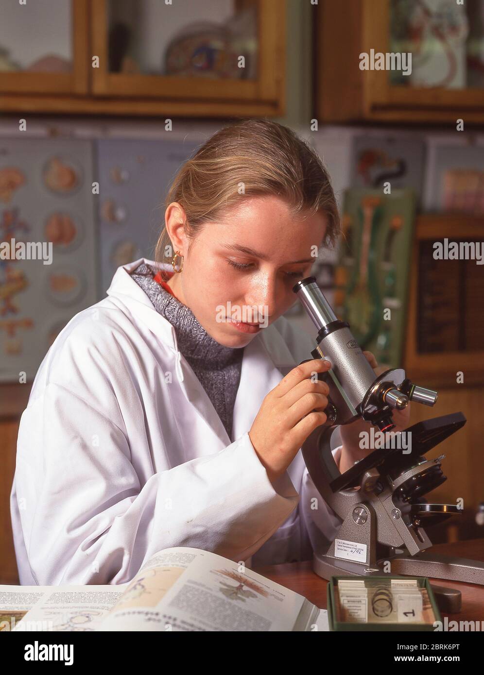 Étudiante féminine au microscope en classe, Surrey, Angleterre, Royaume-Uni Banque D'Images