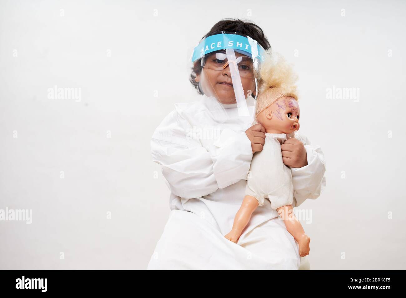 Petites filles portant un masque de protection jouant une poupée de bébé dans la salle de quarantaine de virus de l'hôpital Banque D'Images