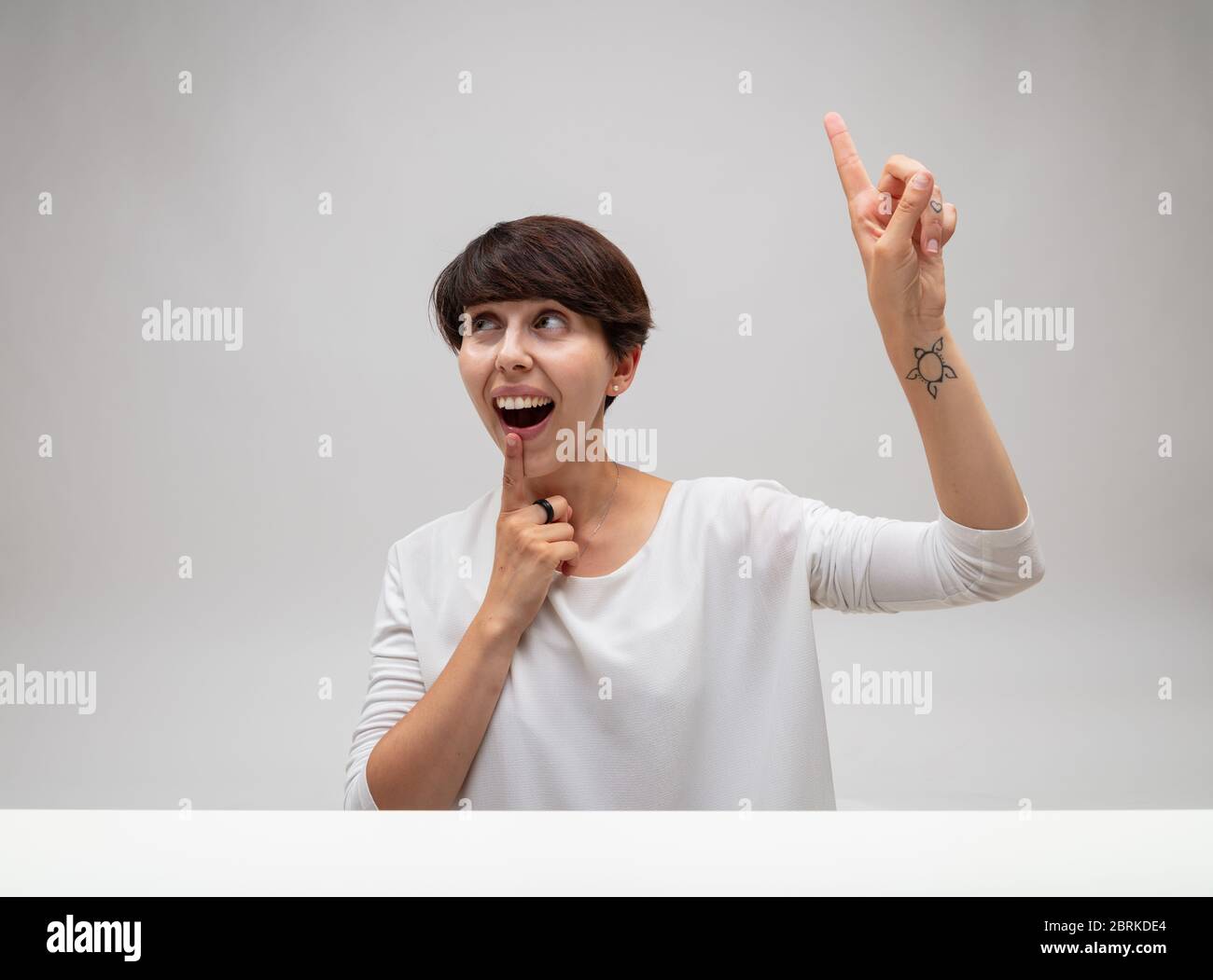 Femme ayant un moment eureka comme elle résout un problème ou a une idée d'inspiration pointant au-dessus de sa tête avec son doigt à sa bouche avec une animation Banque D'Images